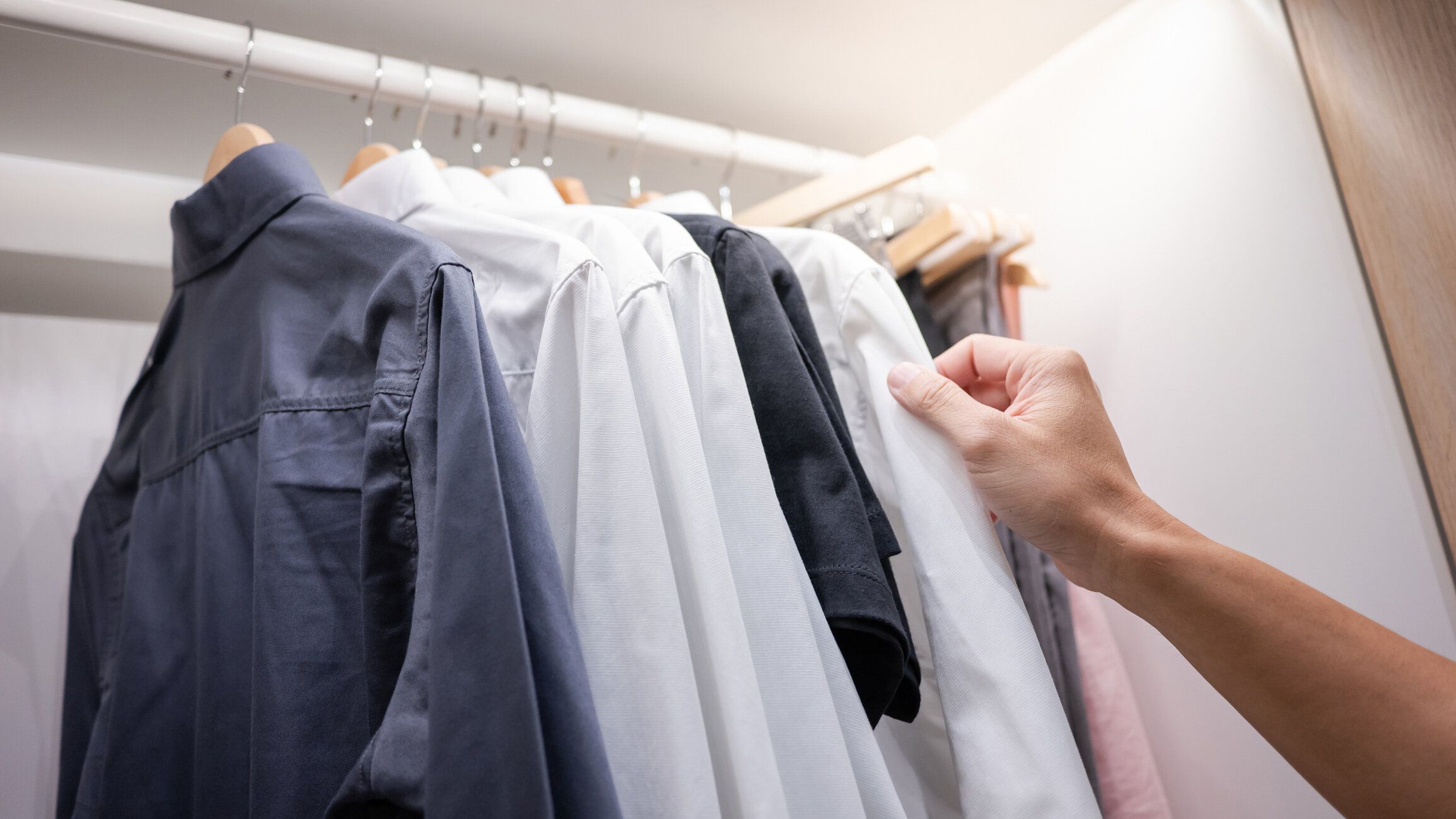 クローゼットの中のシャツを選ぶ男性の手
