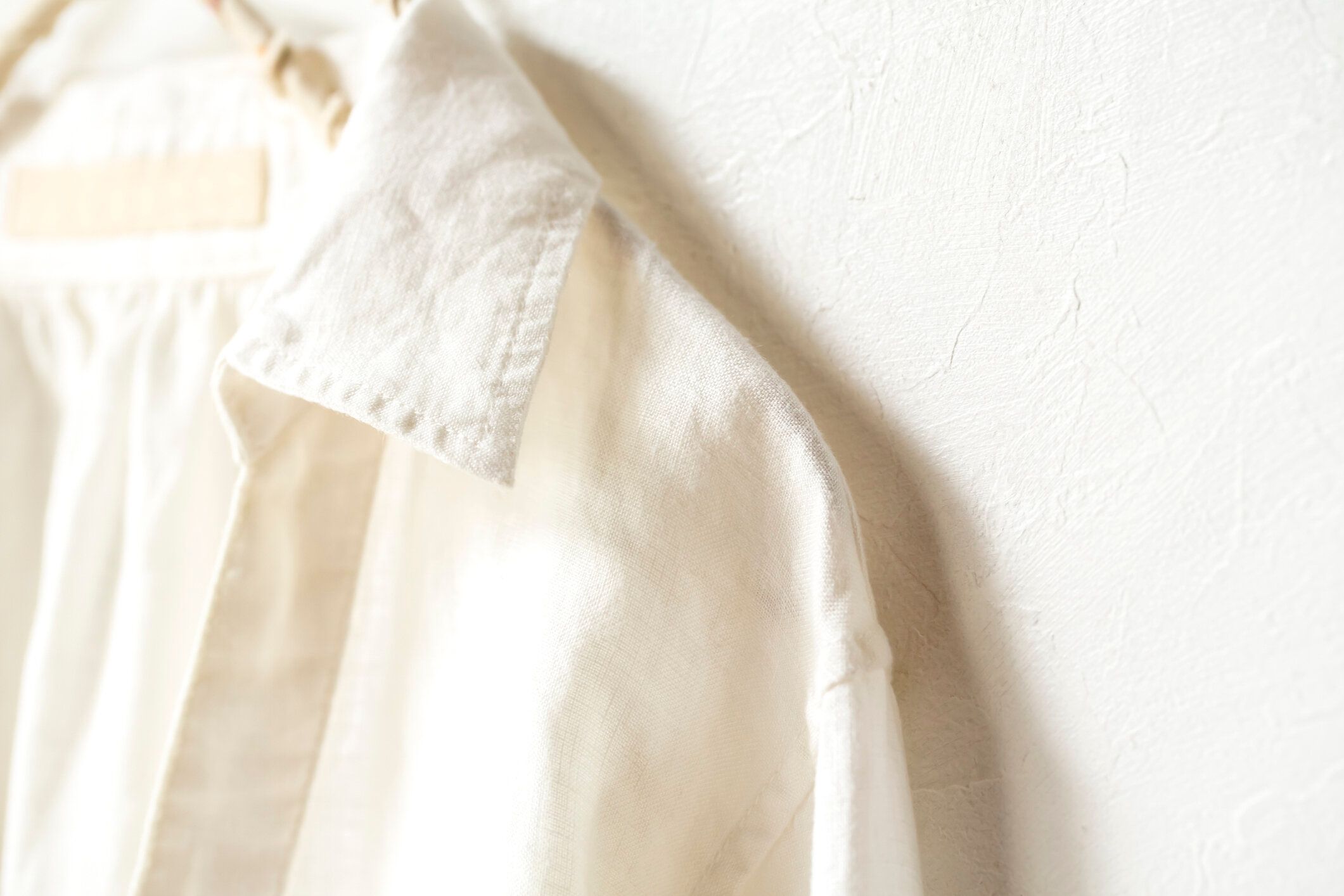 白い背景に衣類ハンガーにぶら下がっている白いブラウスやシャツ。閉じて