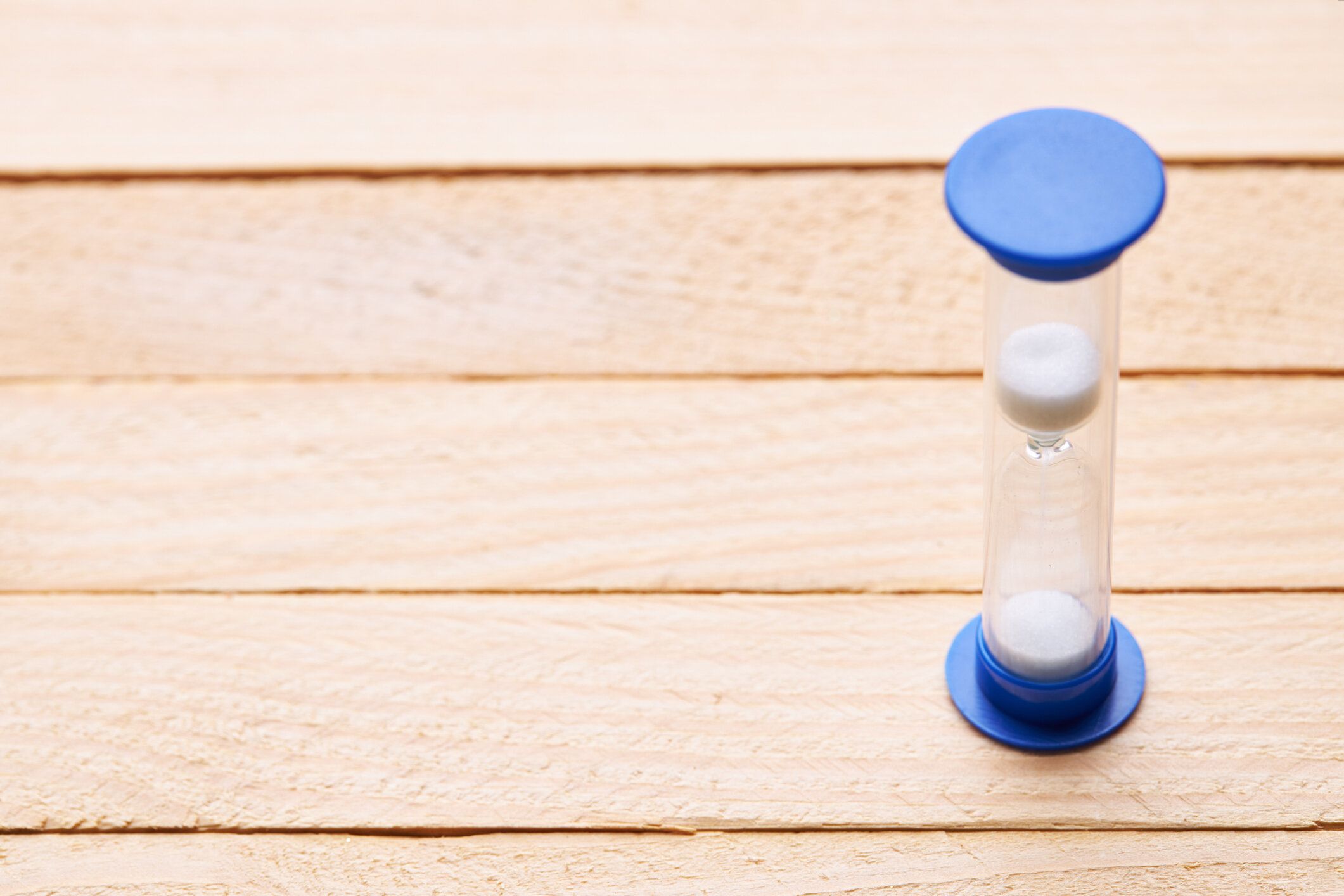 木製の机の上に砂時計1分。コピースペース。時間の最小概念