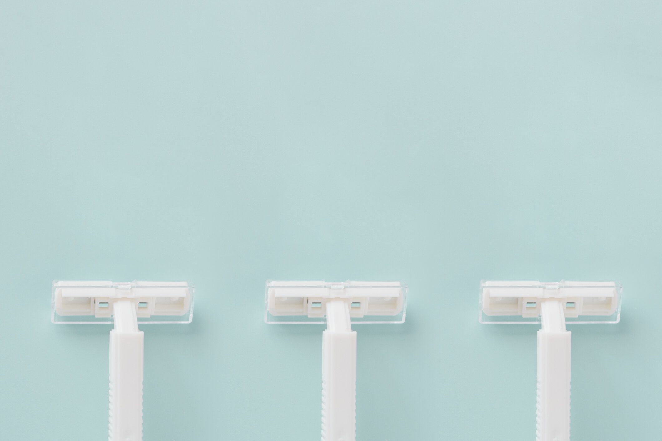 青い背景に使い捨ての白いプラスチックかみそりコピー スペース