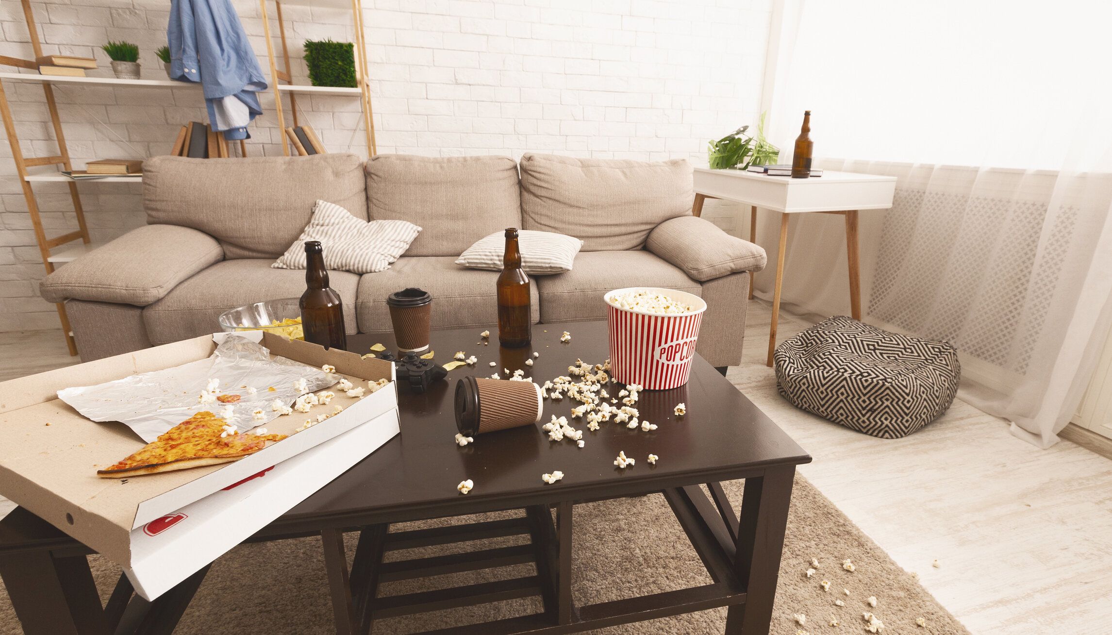 パーティーの後の部屋のカオス。ビールボトル、ポップコーン、ピザ