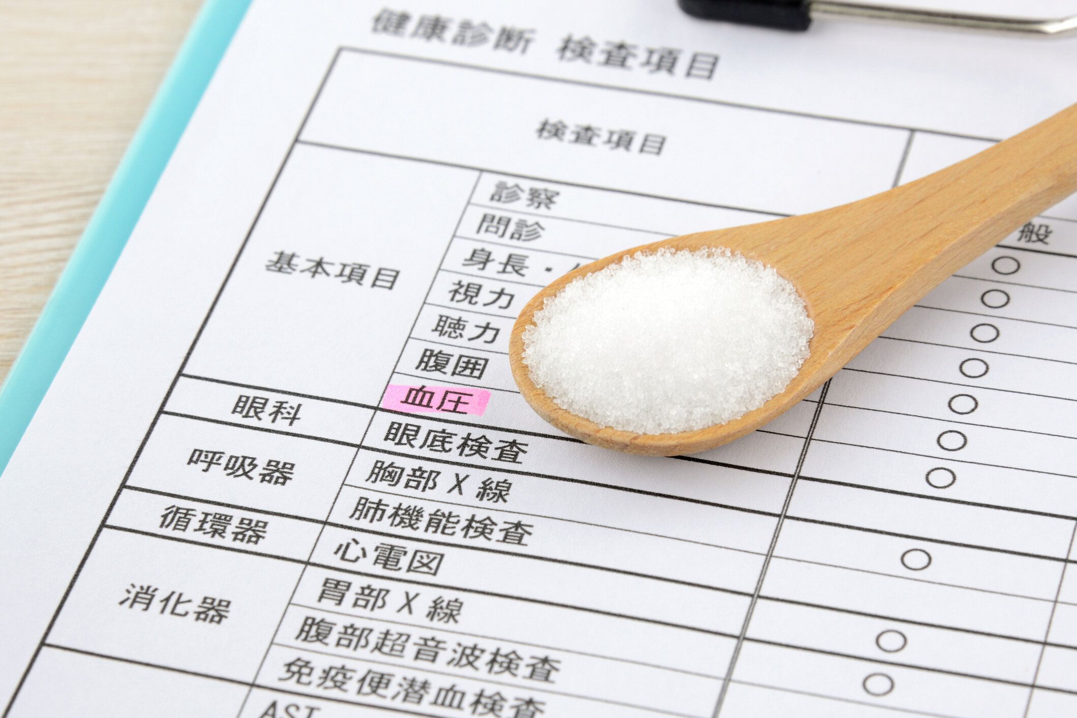 血圧を強調した日本の健康診断シートと塩のスプーン