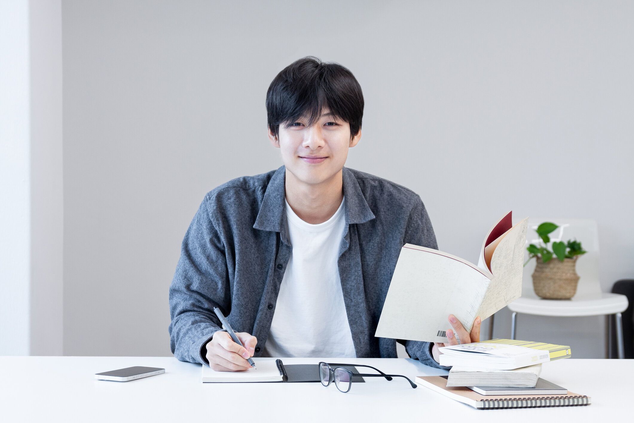 アジアの若い韓国人学生は、試験や試験の準備をする図書館で本を読みながらメモを取りながら勉強します。