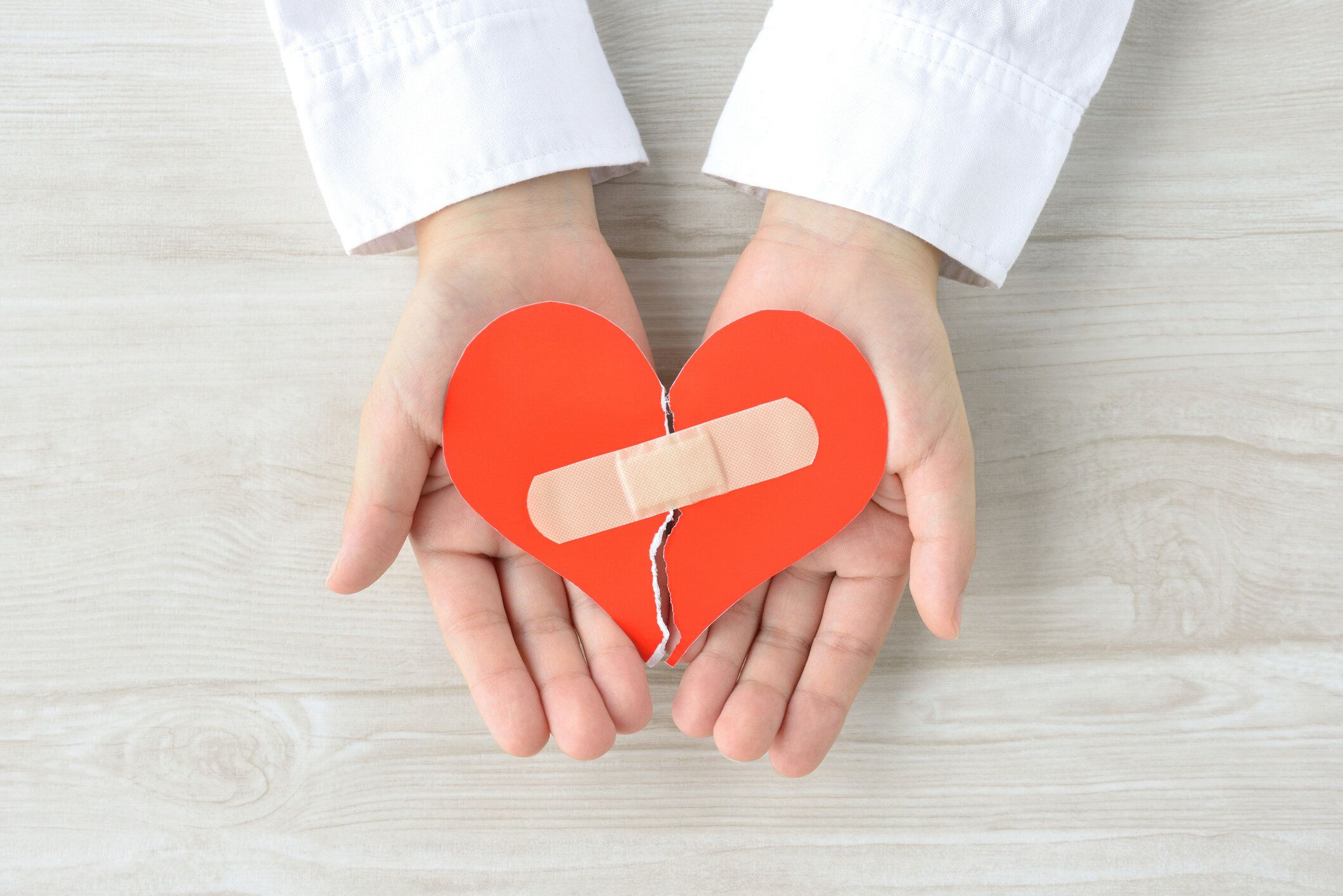 子供の手で覆われた接着剤石膏で引き裂かれた心臓