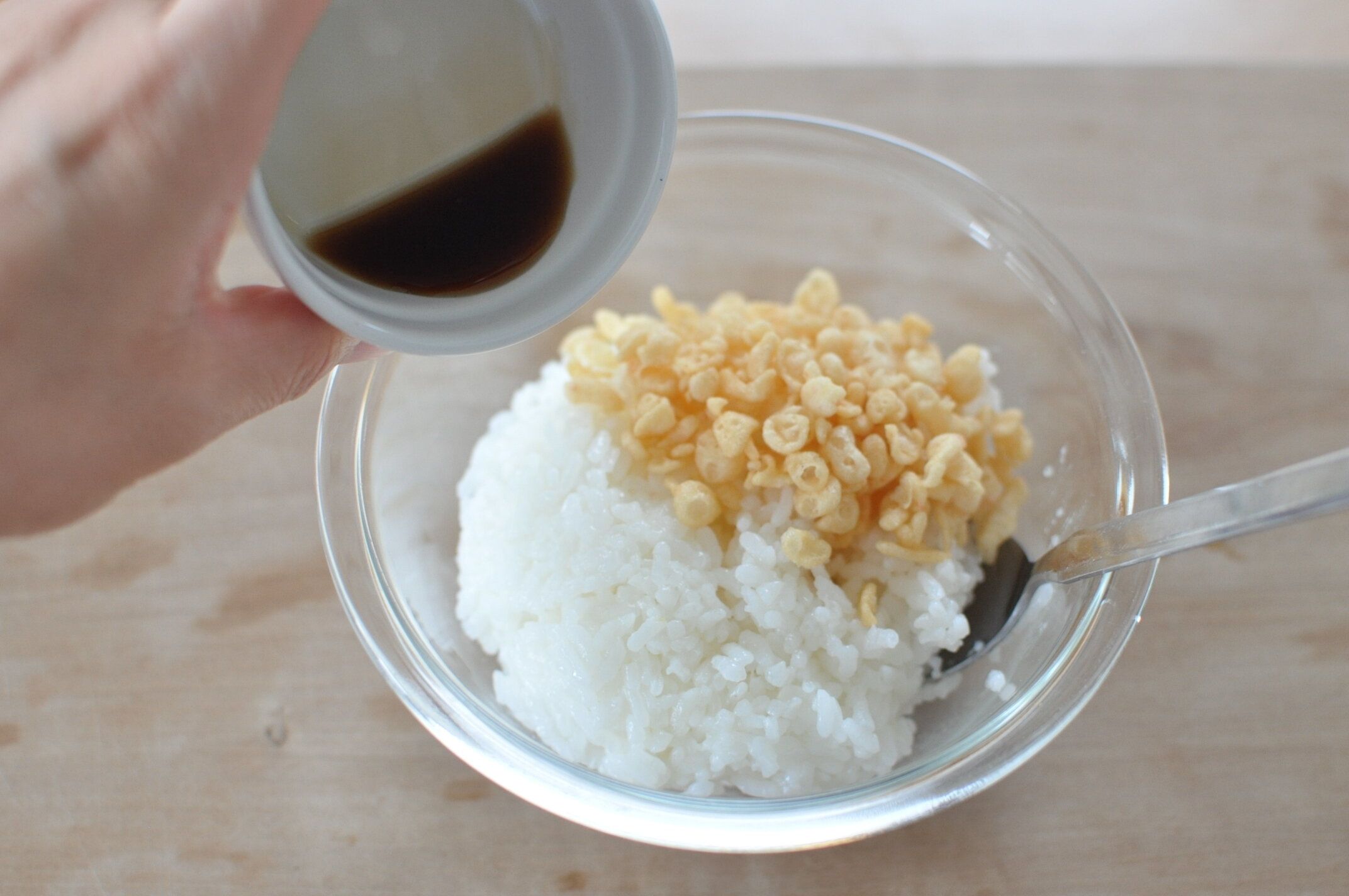 ご飯と揚げ玉を入れたご飯に、麺つゆを加える様子