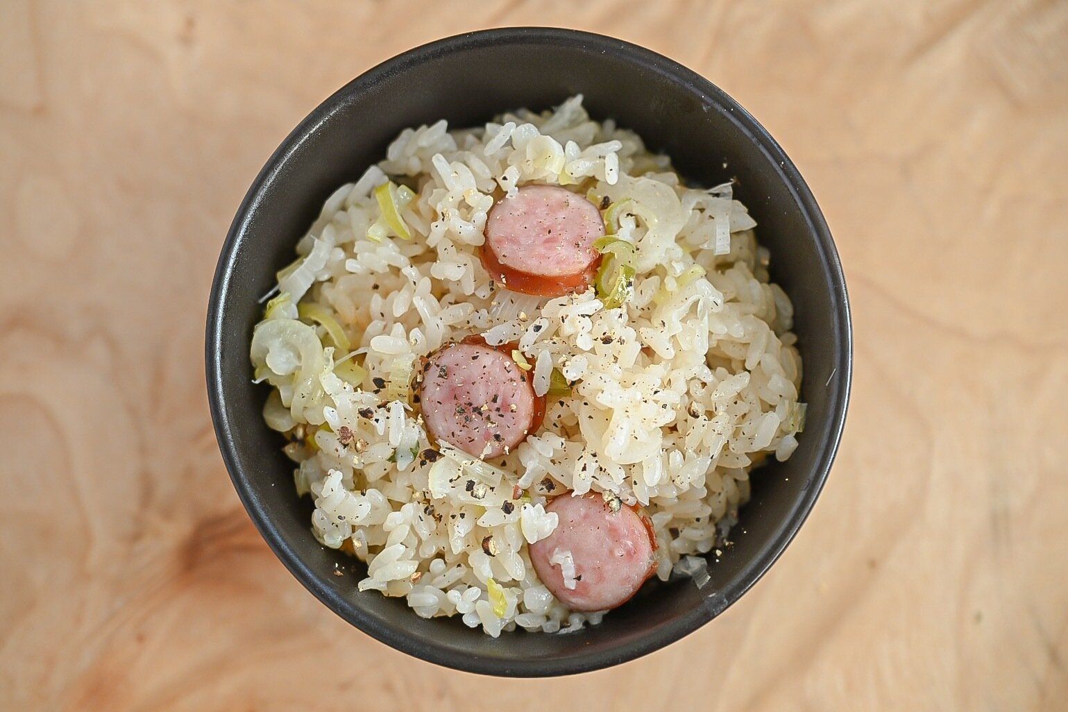 黒い茶碗に入ったソーセージの炊き込みごはん