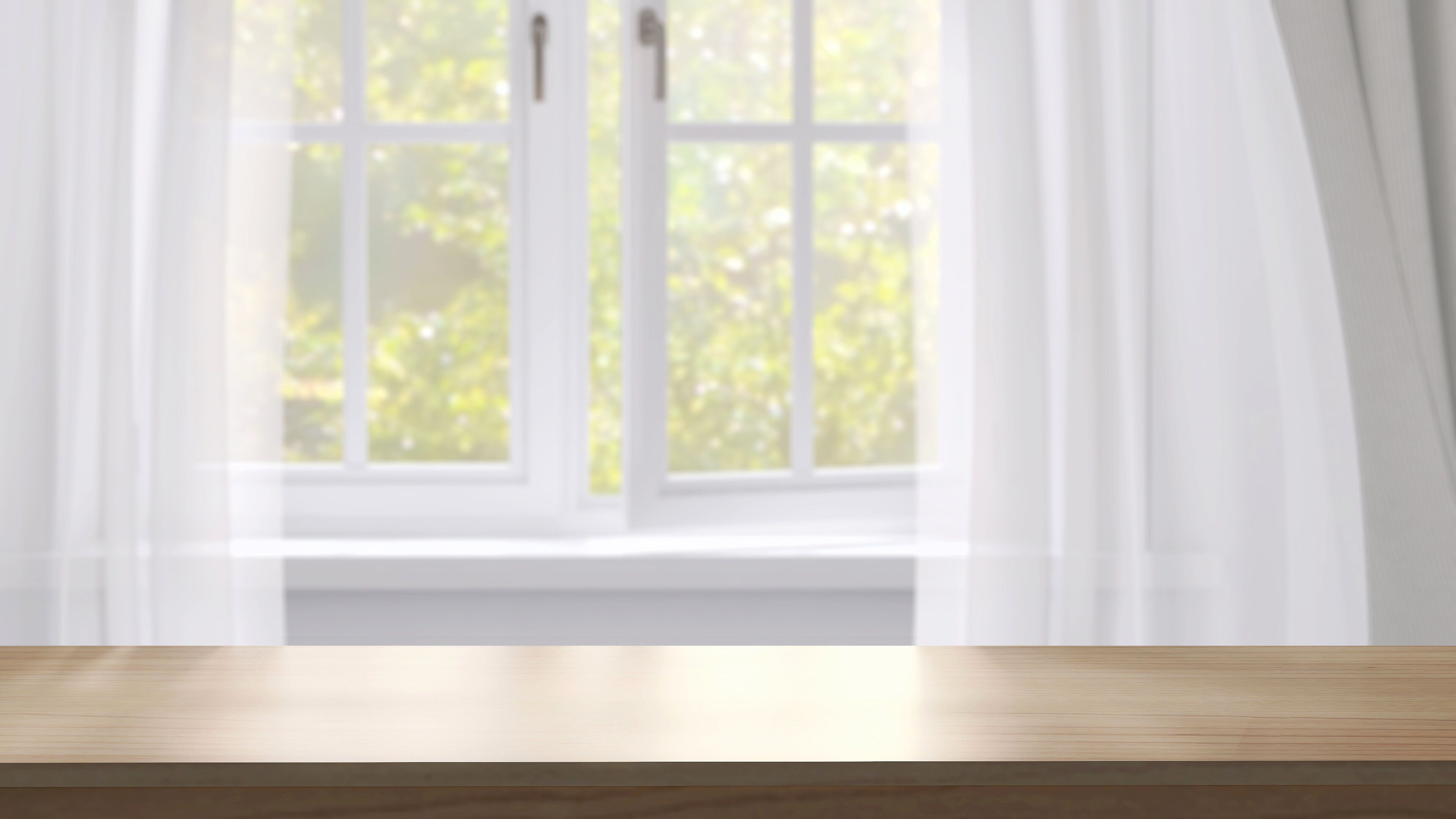 日差しが降り注ぐ背景に窓、白いカーテン、木が置かれた木製の卓上