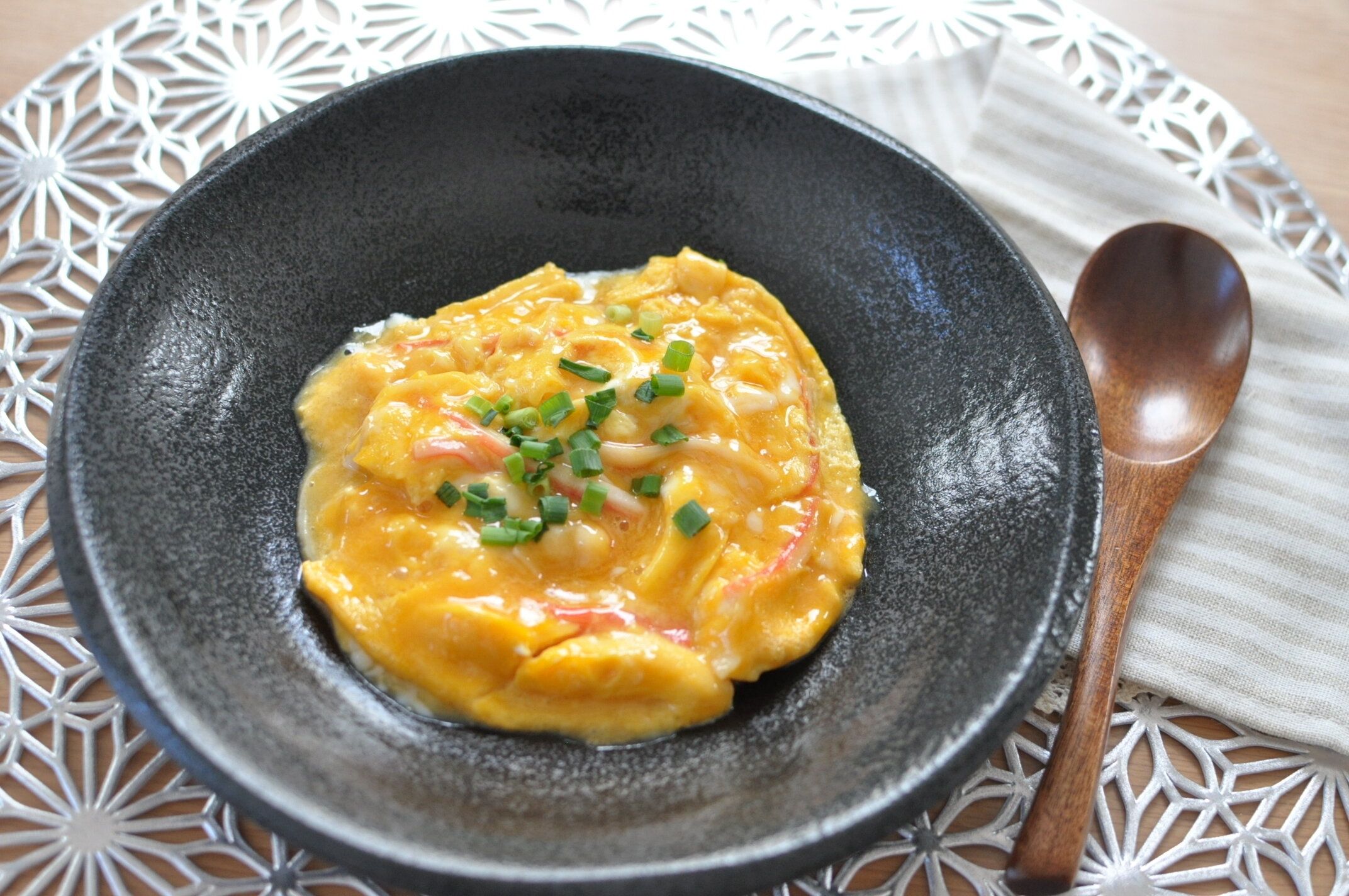 とろとろ卵のかに玉を黒い器に盛り付けた様子