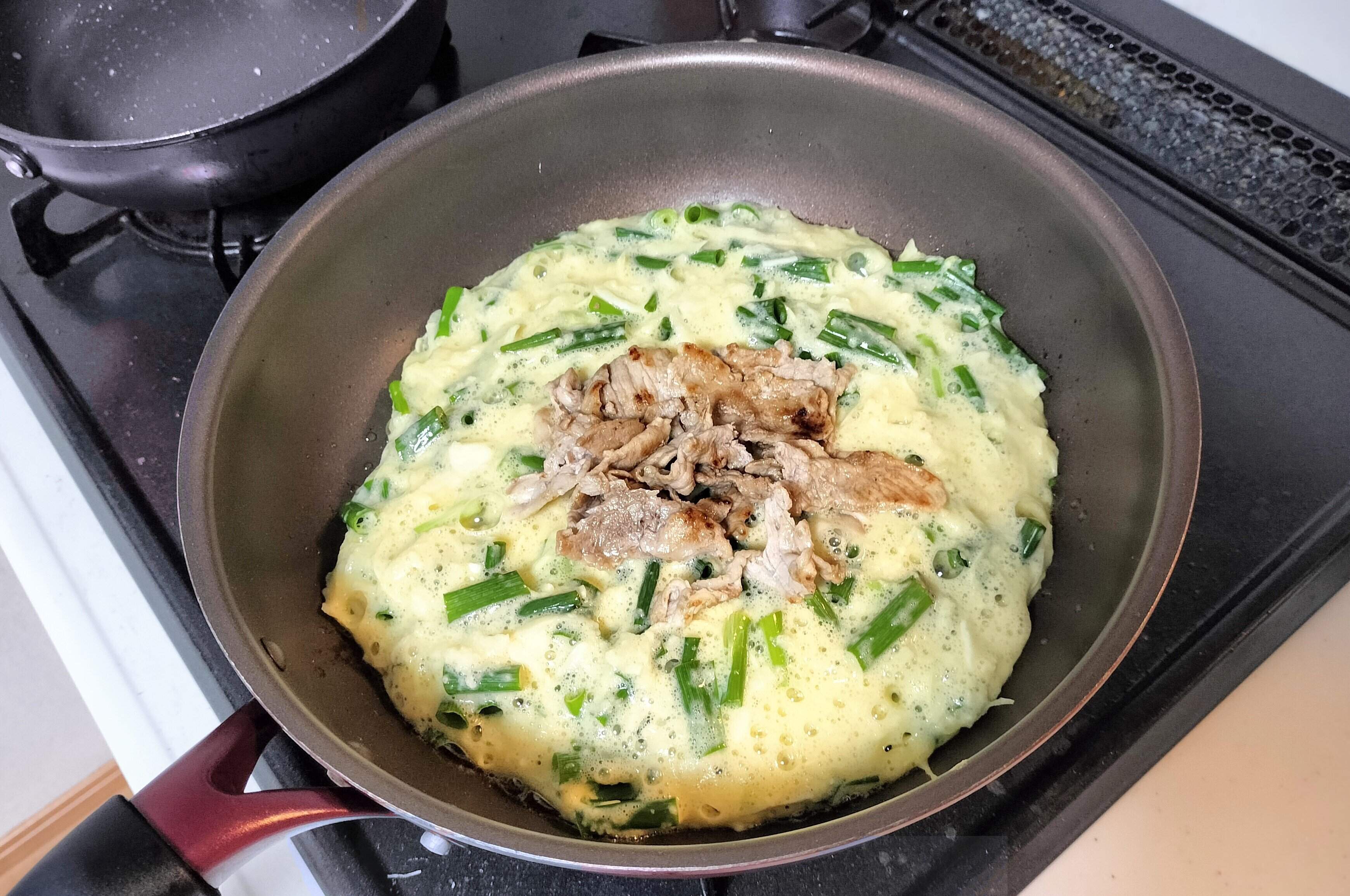 フライパンにお好み焼きのタネをひろげ、豚肉をのせる