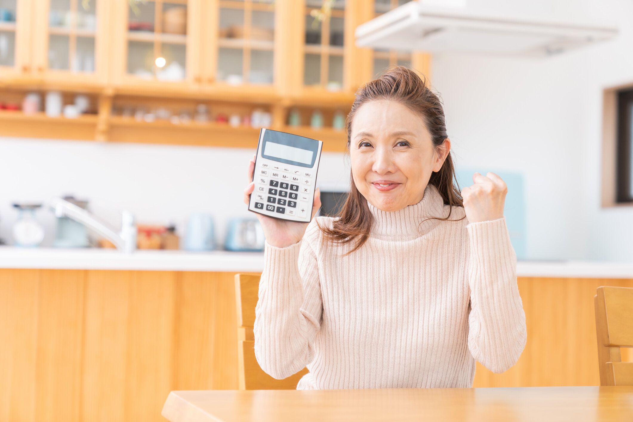 電子電卓を持つシニア年齢の女性、笑顔