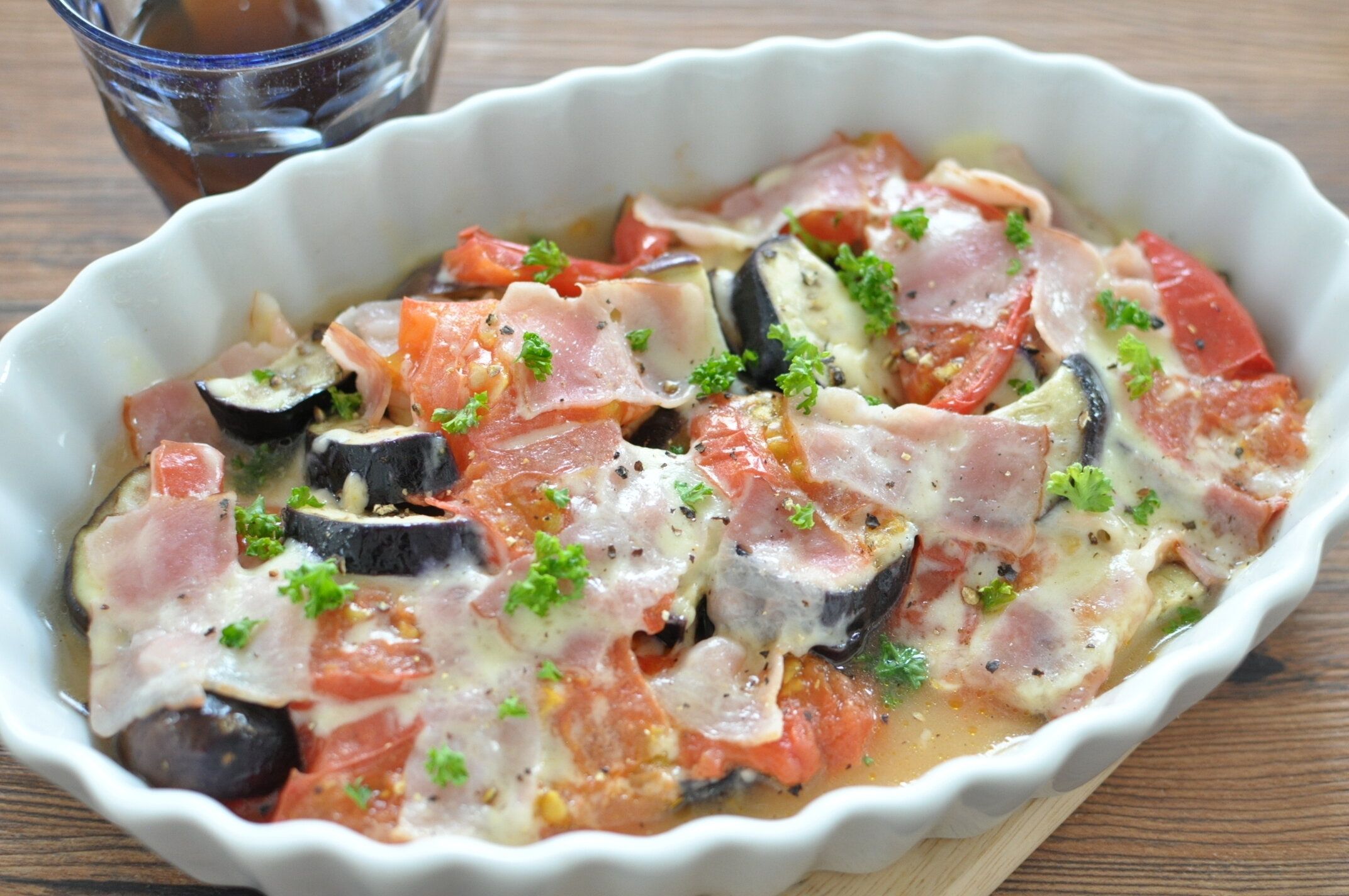 白い耐熱皿に盛り付けられたレンチンなストマベーコンのチーズ焼き