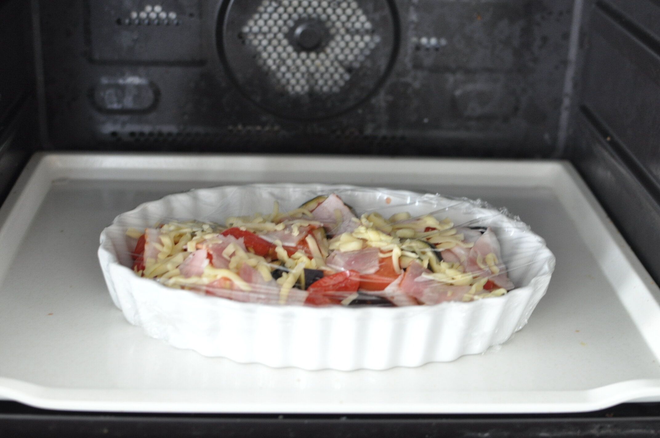 耐熱皿にラップをかぶせて、レンジに入れた様子