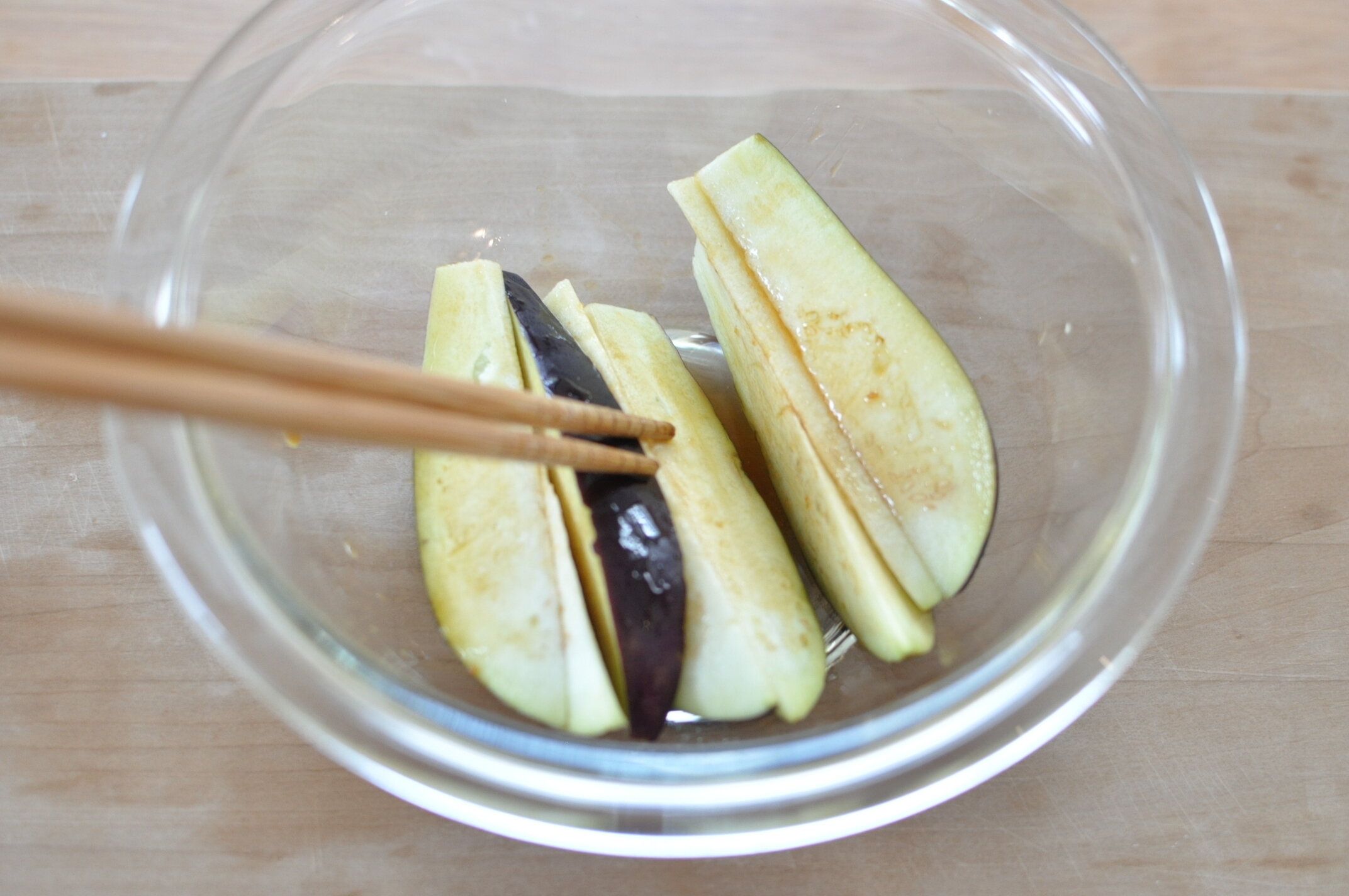 なすを耐熱ボウルにいれ、焼き肉のタレを絡める様子