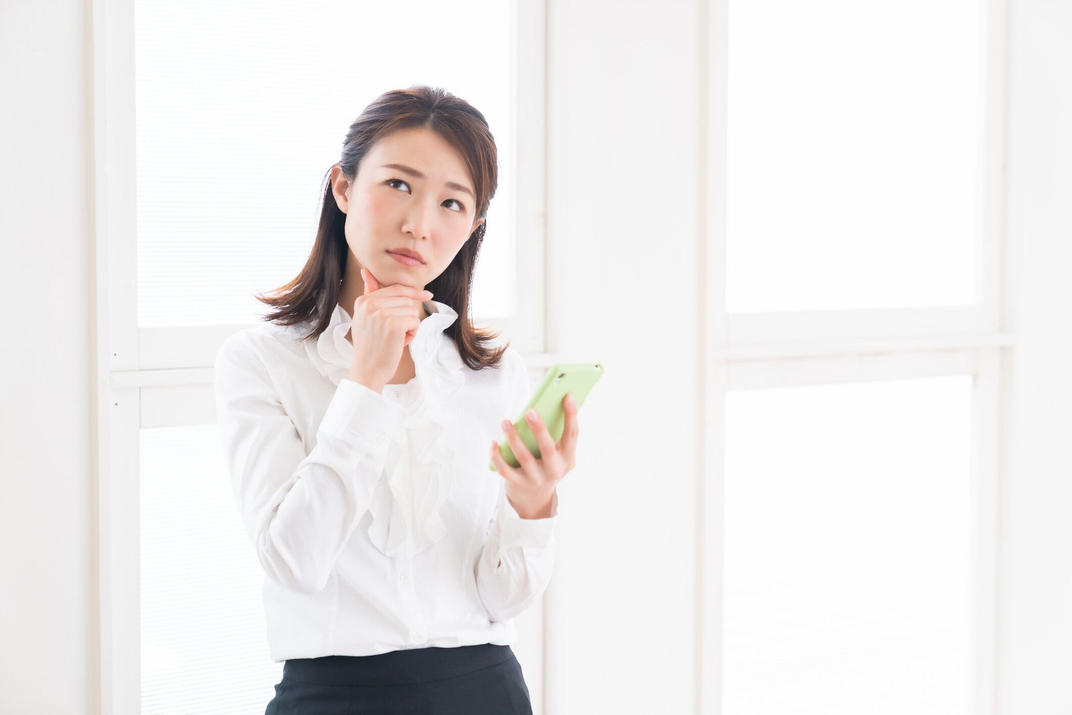 スマートフォンを見て魅力的なアジアの女性は、考える