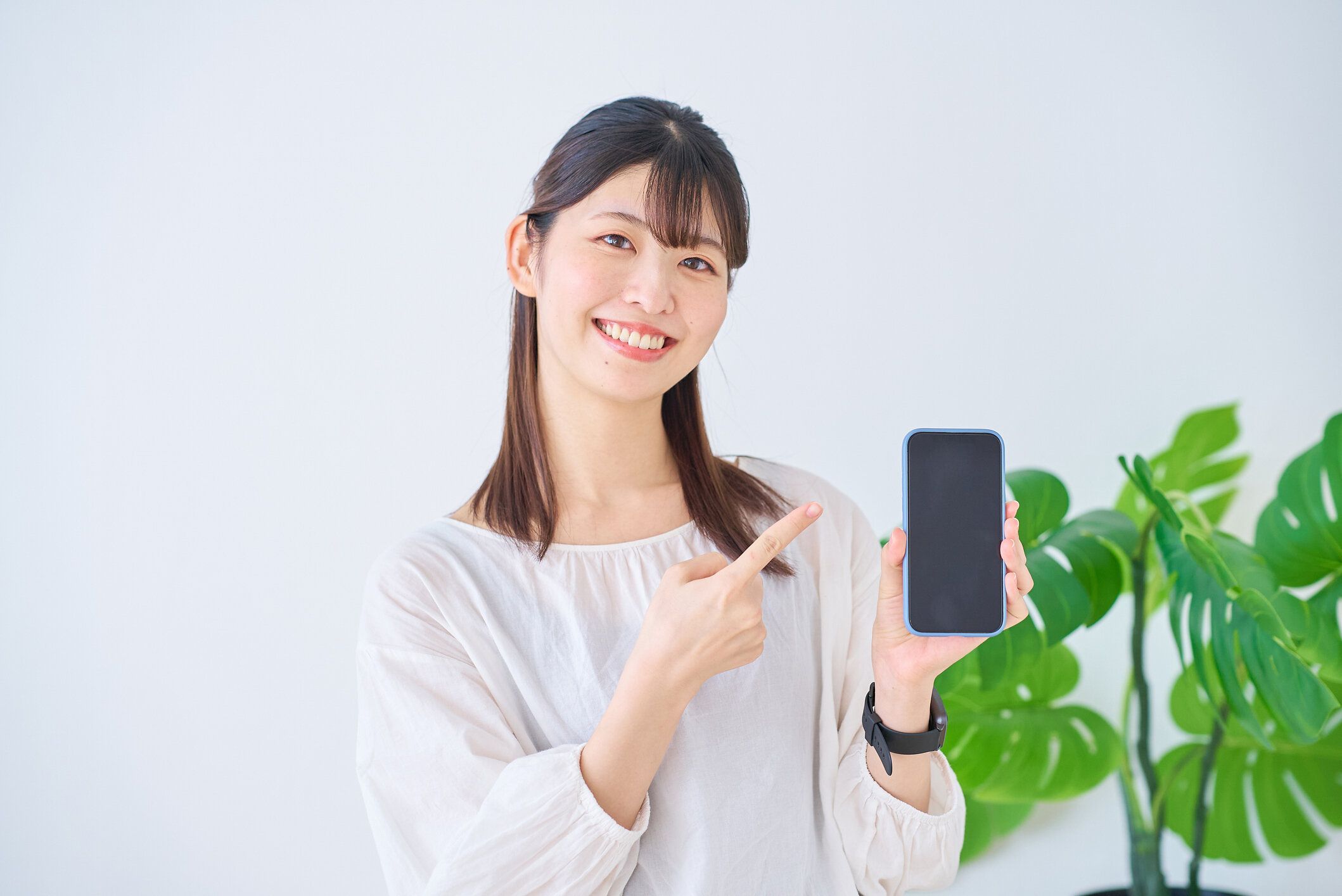 スマートフォンを指差す若い女性