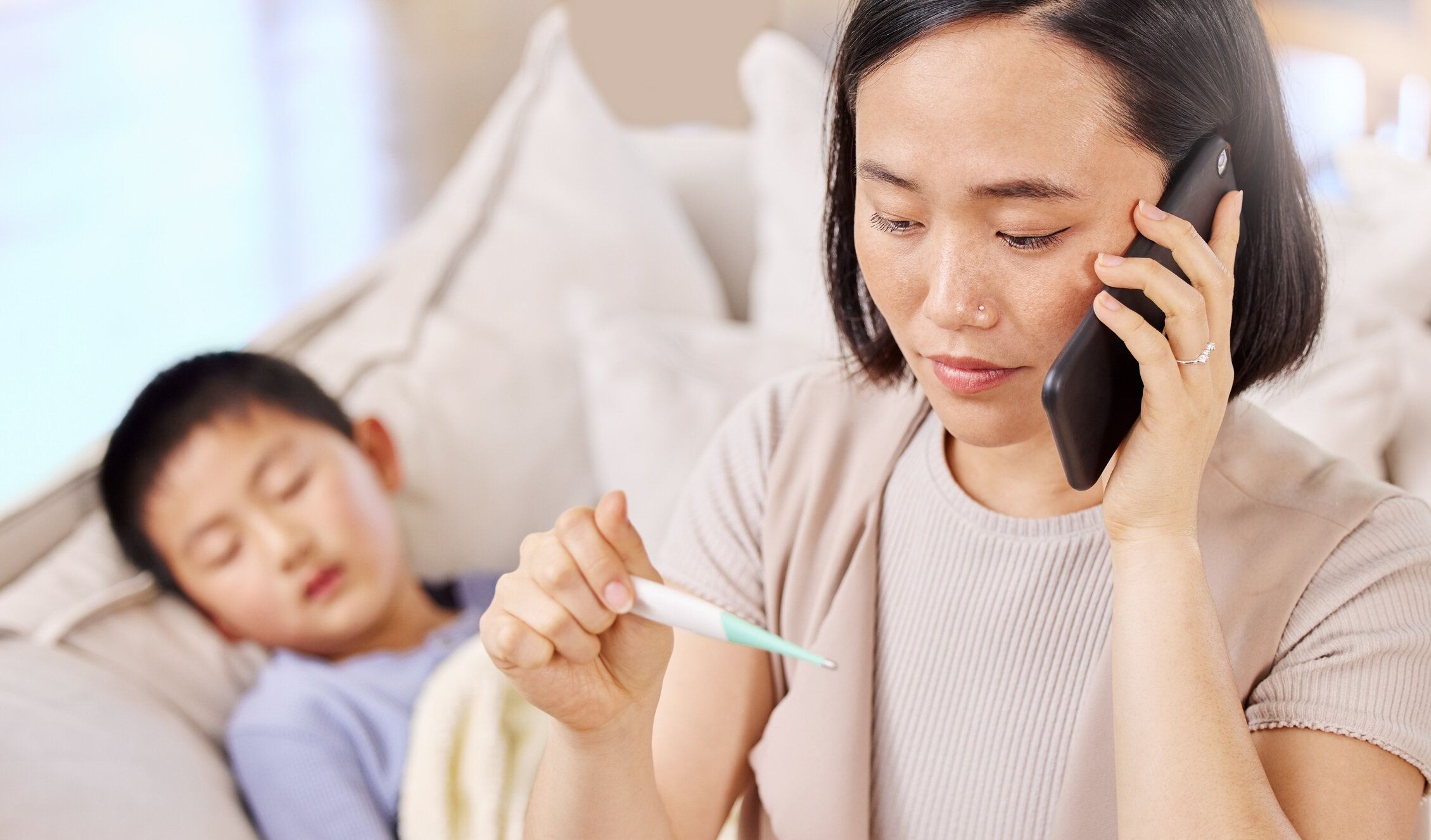 子供の体温を取った後、電話で話している女性のショット