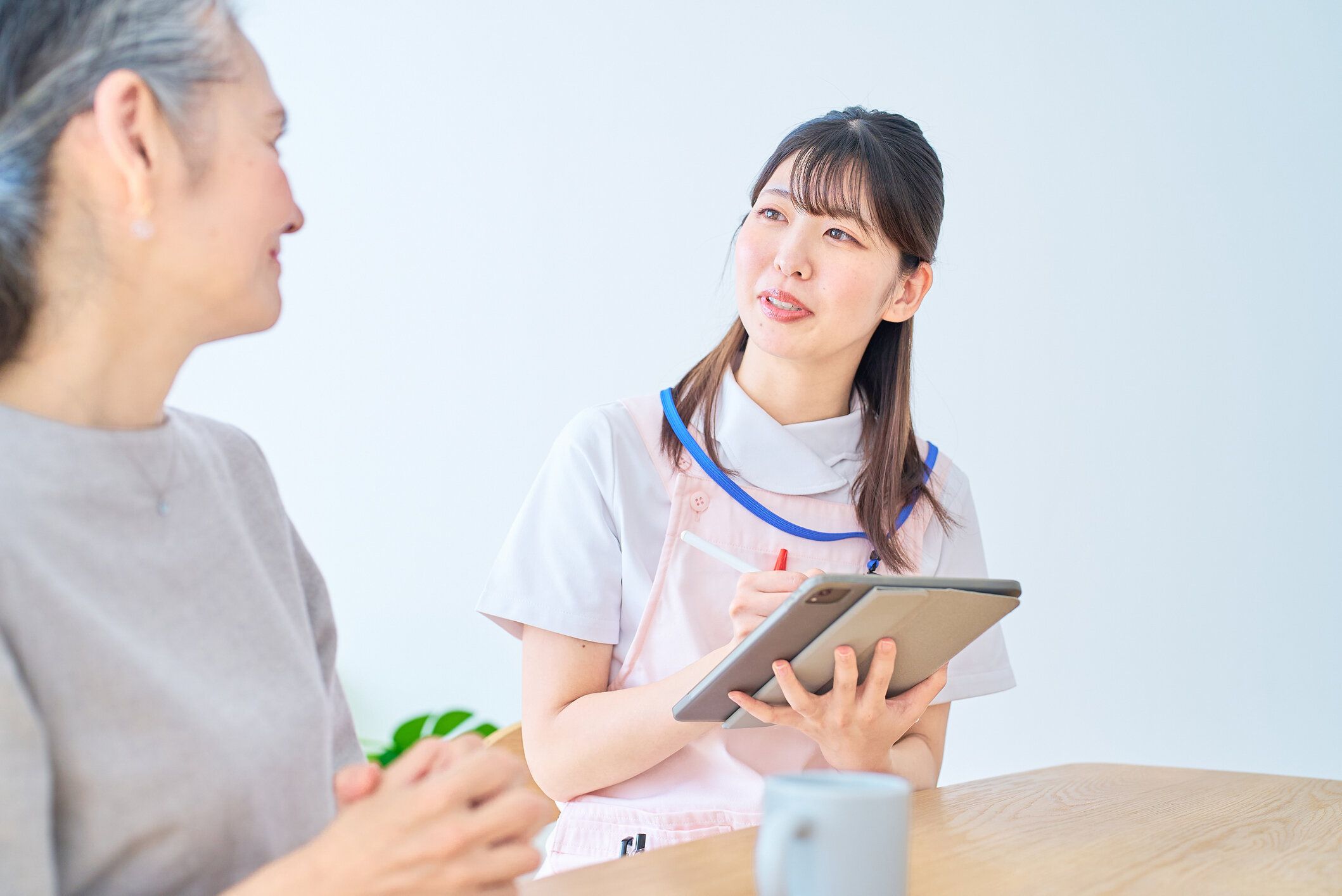 エプロン姿の若い女性と家で会話をする年配の女性