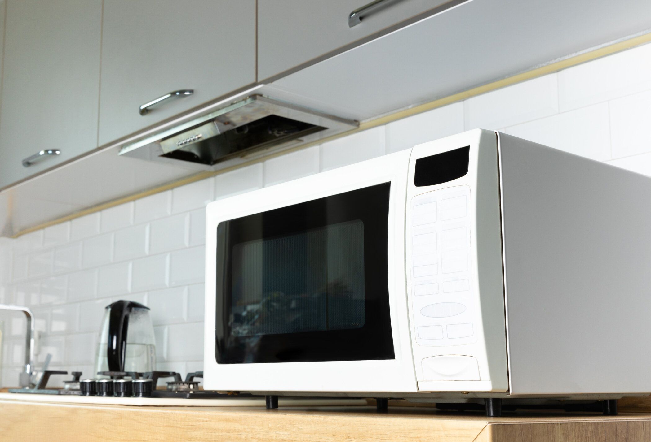 キッチンのカウンタートップにあるモダンな白い電子レンジ。キッチンで毎日電子レンジを使う。料理のコンセプト。