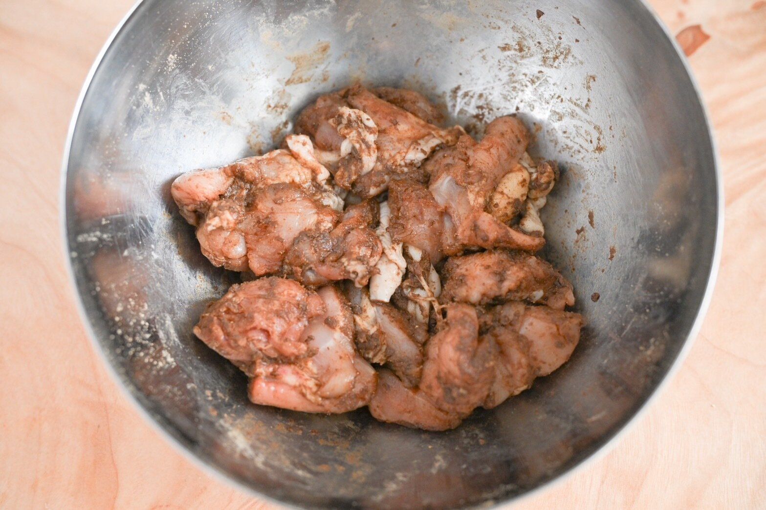 ボウルに入ったマリネシーズニングと和えたもも肉