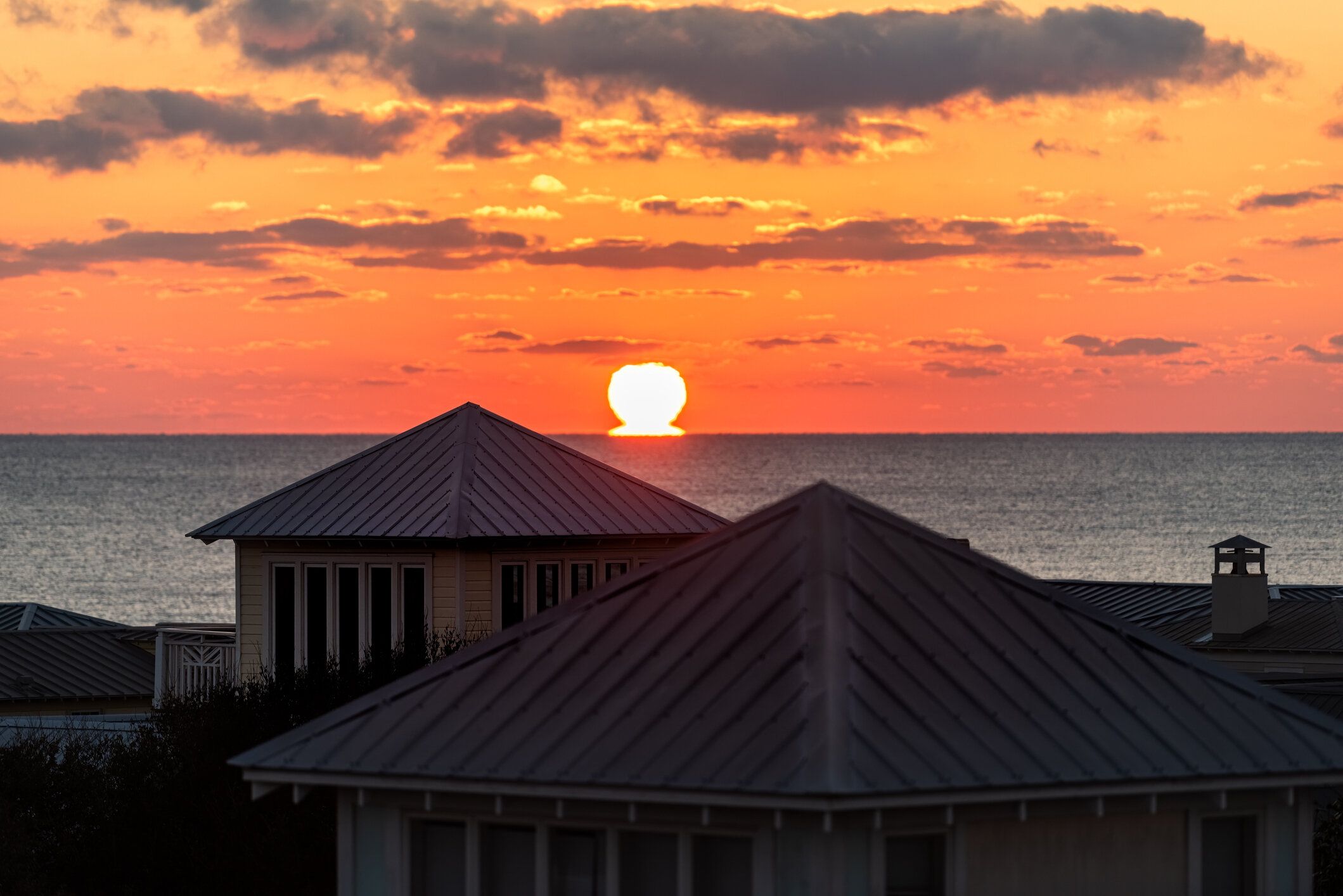 屋上テラスの建物から海辺、フロリダ州メキシコ湾の海の風景と地平線上のカラフルな黄色の夕日サンオメガの空中写真は家を収容します