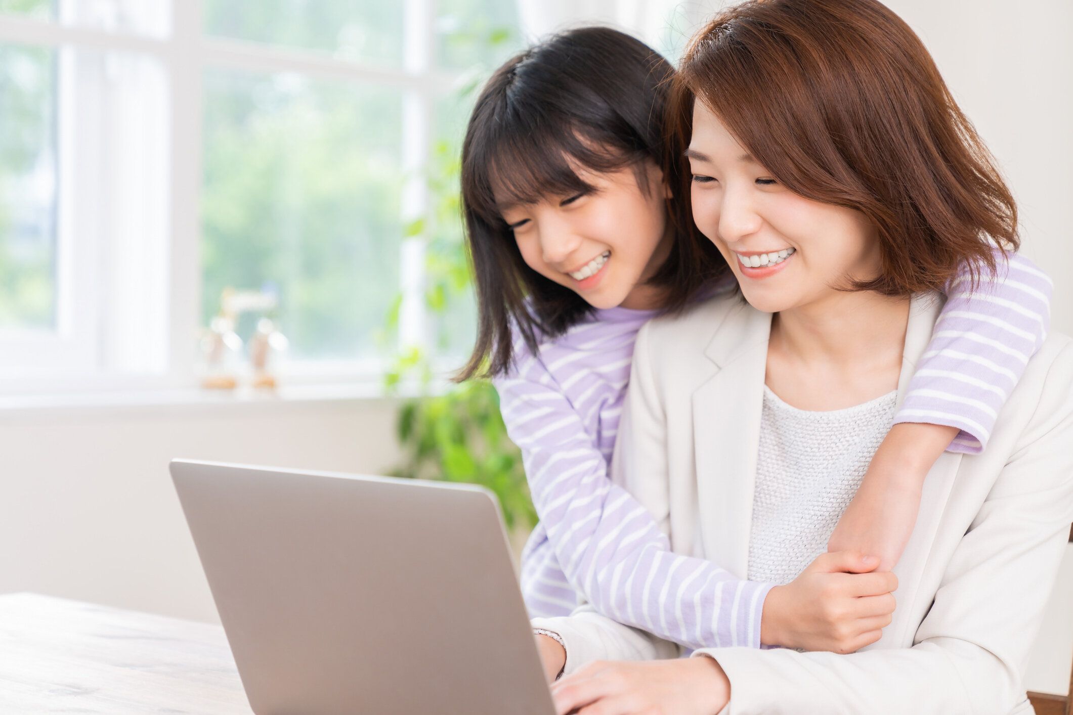 働くお母さんとラップトップコンピュータ、娘