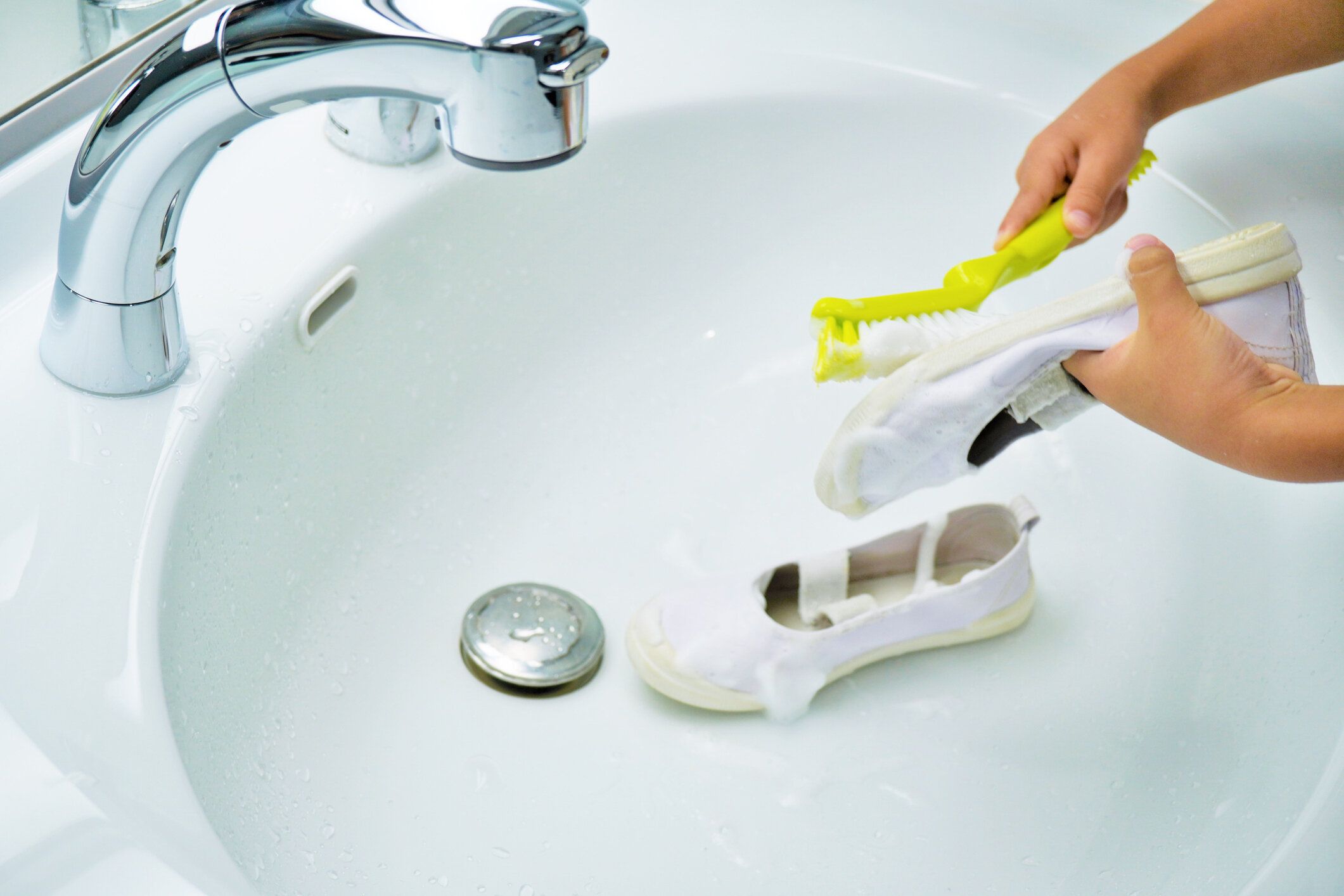 明るい洗面所で靴の裏をブラシでこすろうとする幼い子供