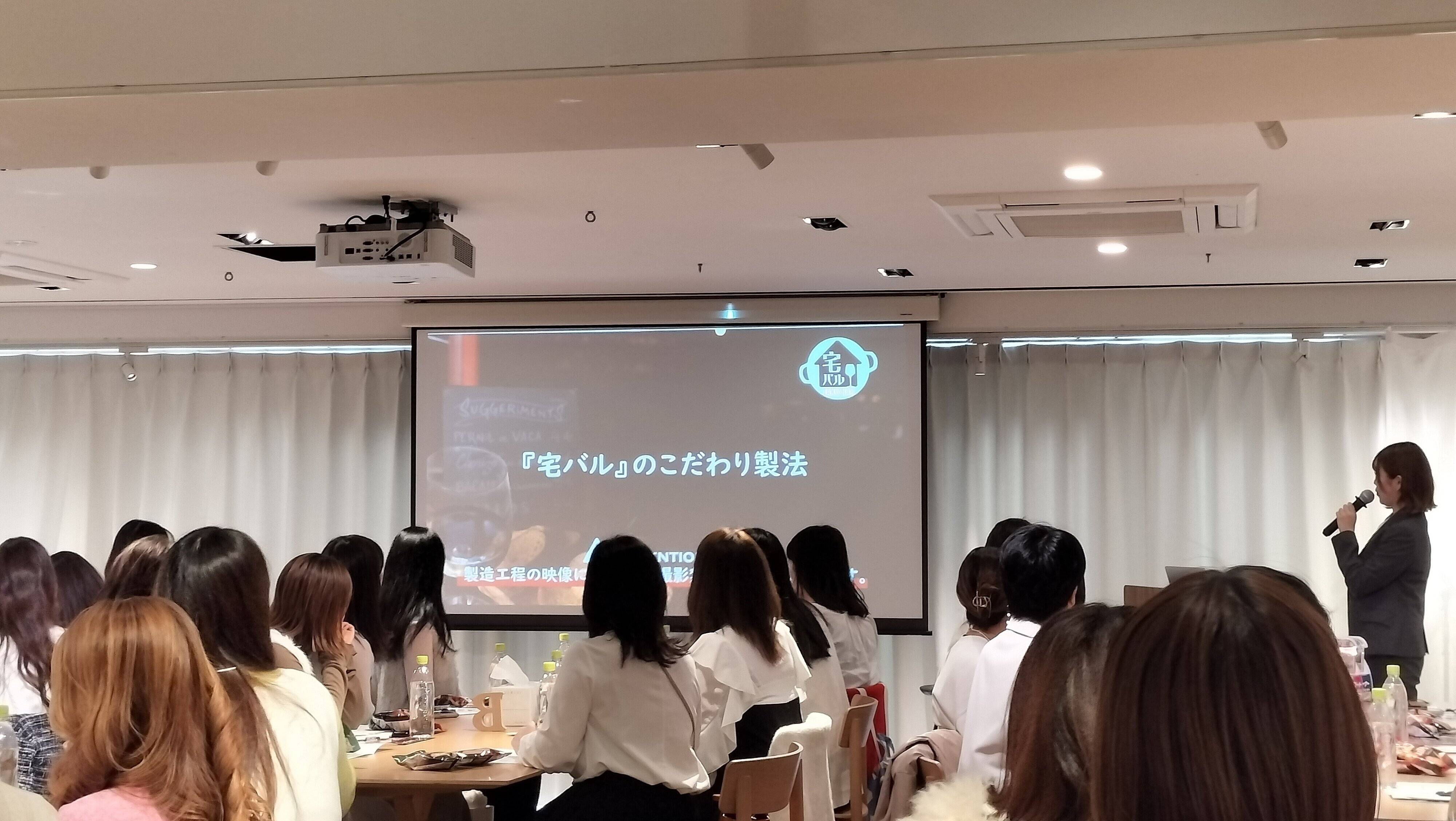 宅バルの詳細をスクリーンを使って説明している様子