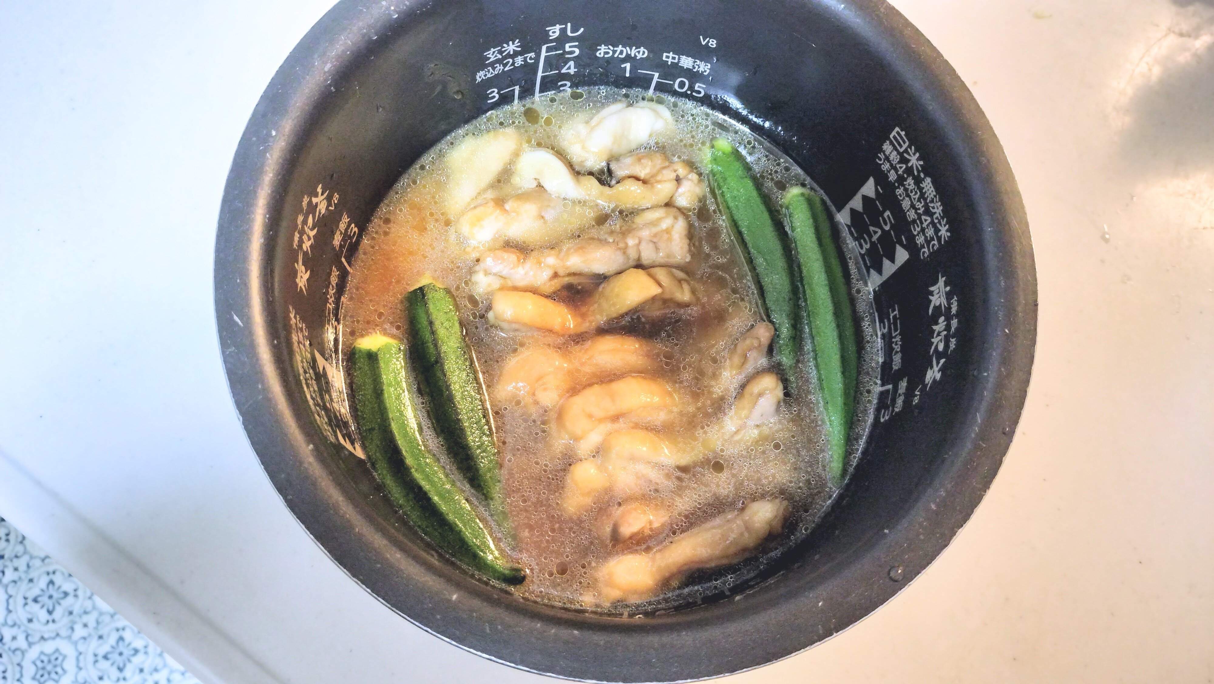 火にかけた鶏肉とたれ、おくらを一緒に炊き込む