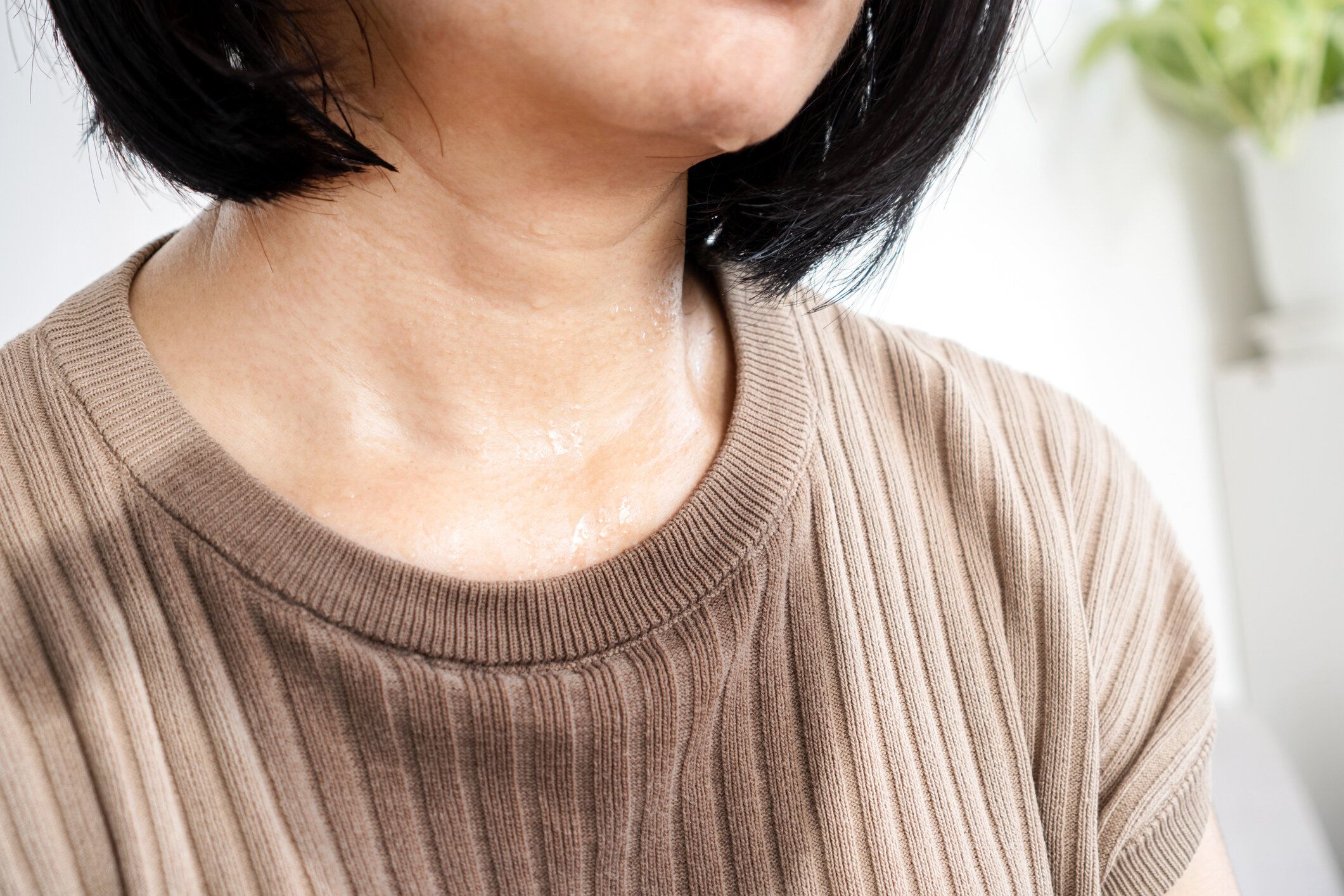 濡れた布で汗をかいた女性が夏の天候で暑く感じる