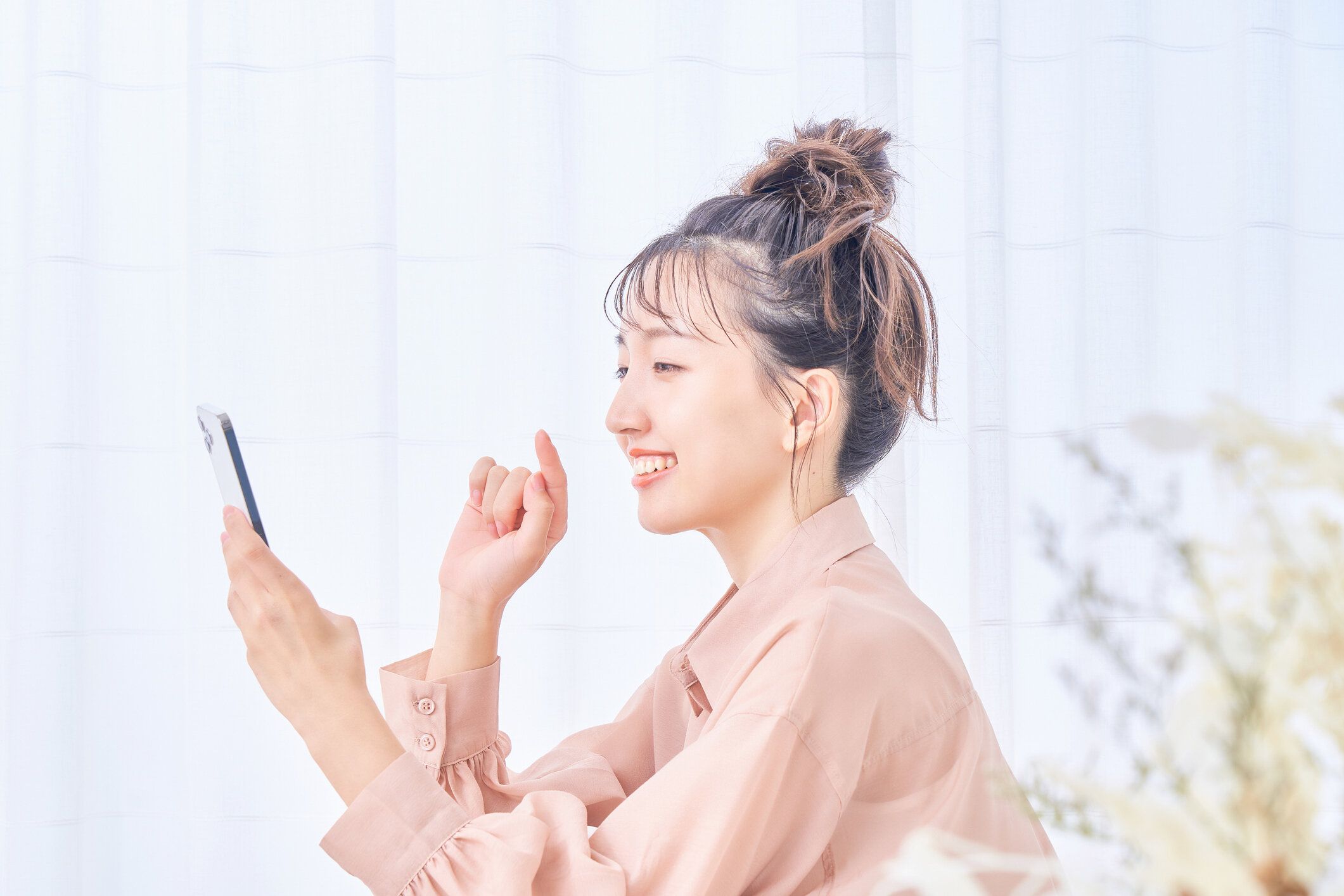 部屋でスマホを使う若い女性