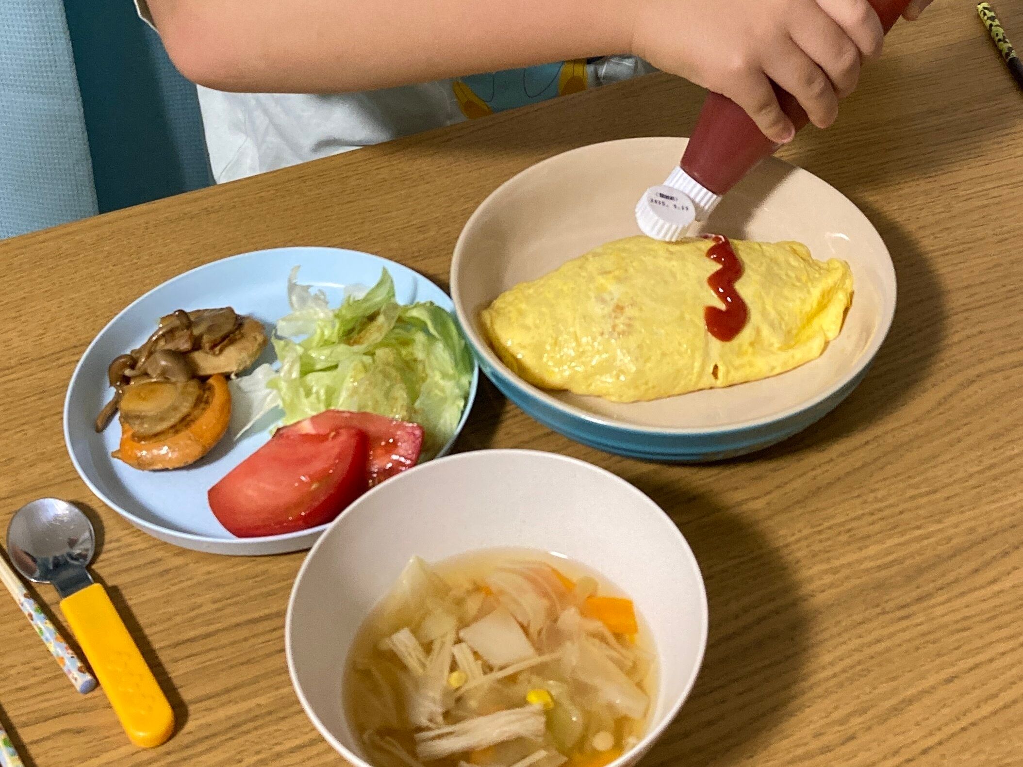 ケチャップでオムライスに味付けをしている子供