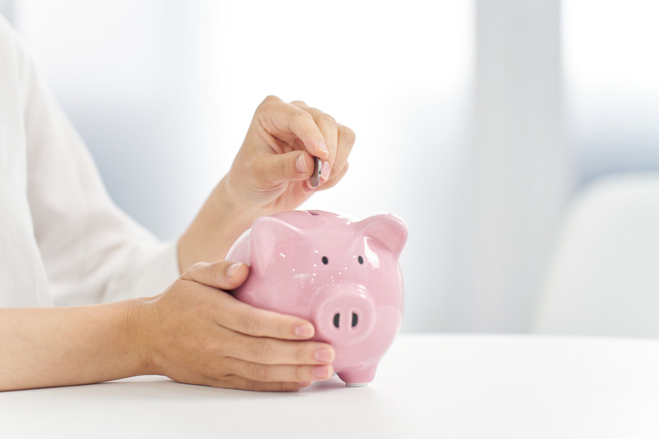 豚の貯金箱にお金を入れる女性