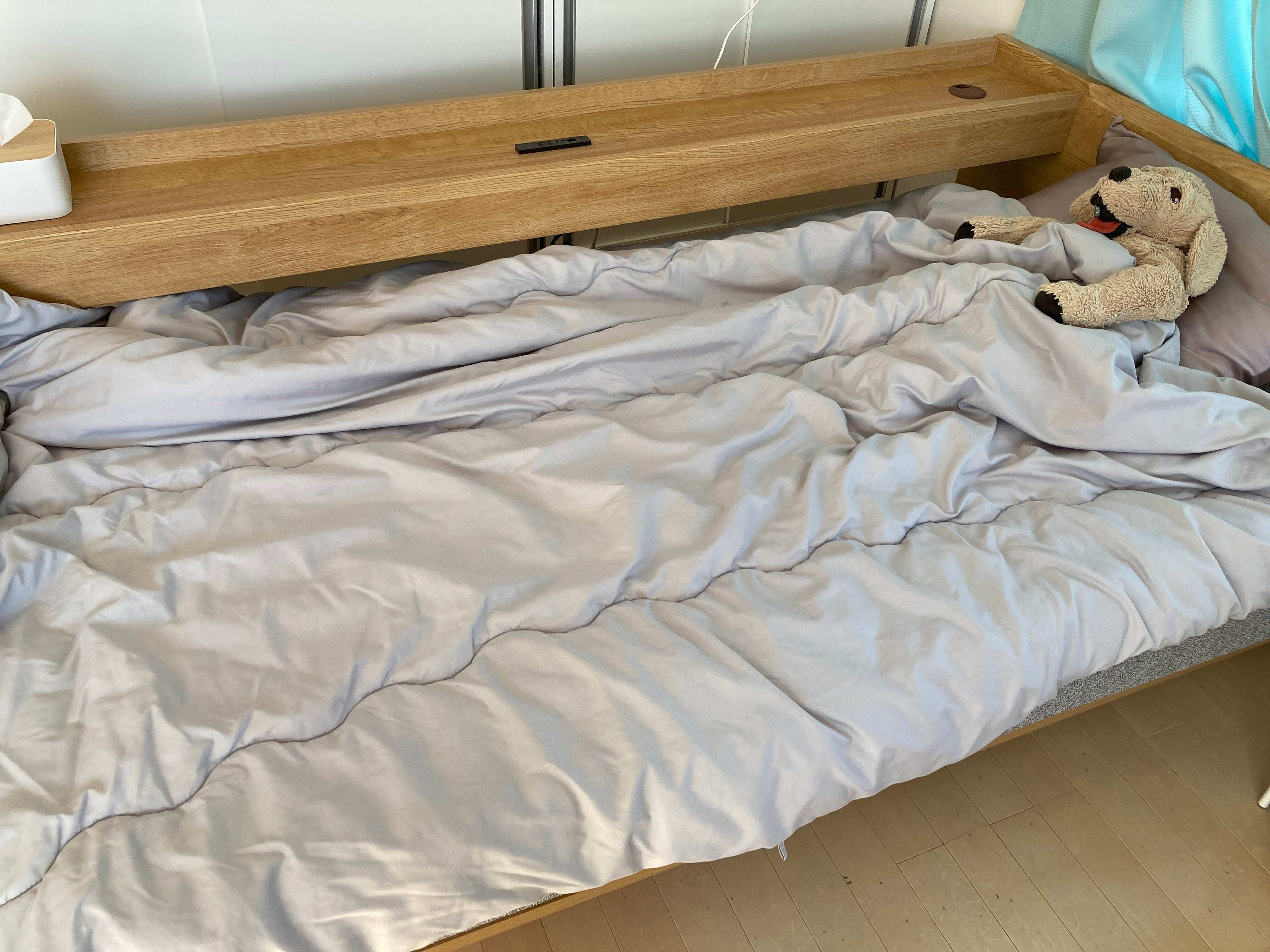 布団にくるまっている犬のぬいぐるみ