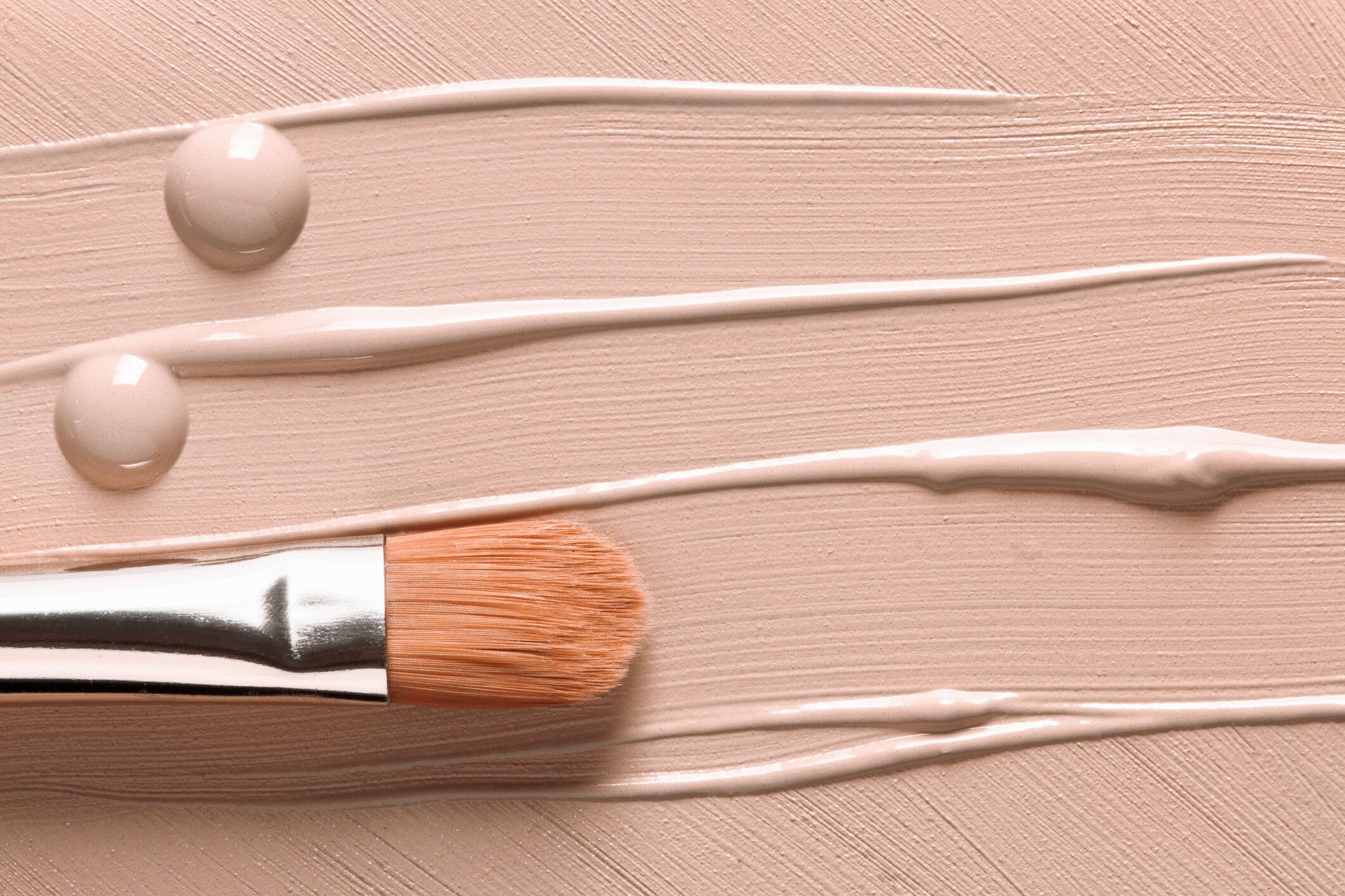 メイクアップの背景。液体基礎テクスチャと化粧品ブラシ