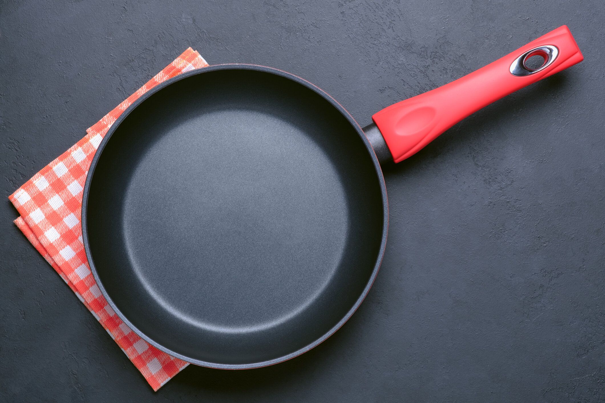 黒い石の背景の上に空のフライパンとナプキン。