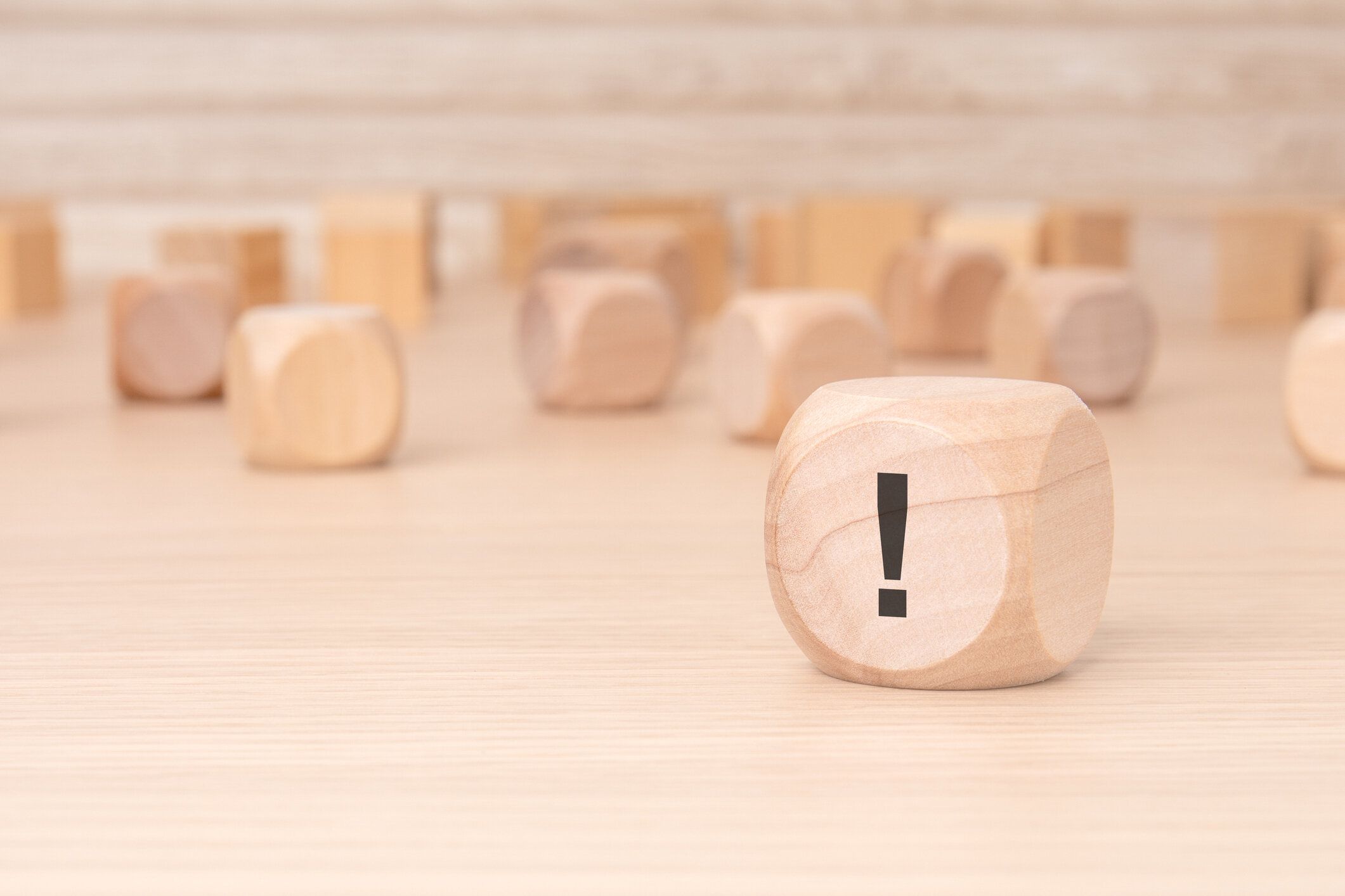 茶色の背景に側面に黒の感嘆符が付いた小さな木製のブロック