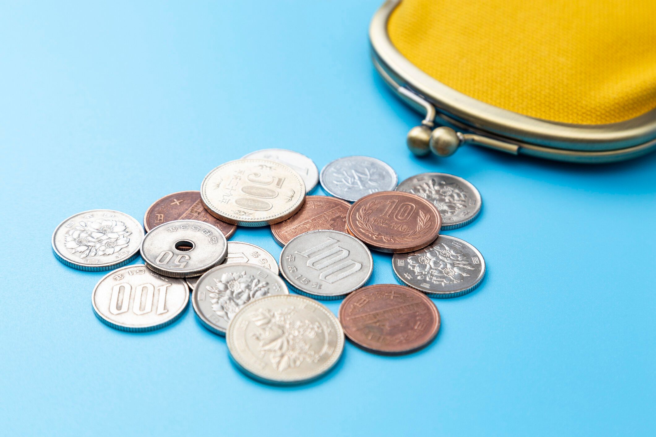 青い背景にコインケースと日本円貨。