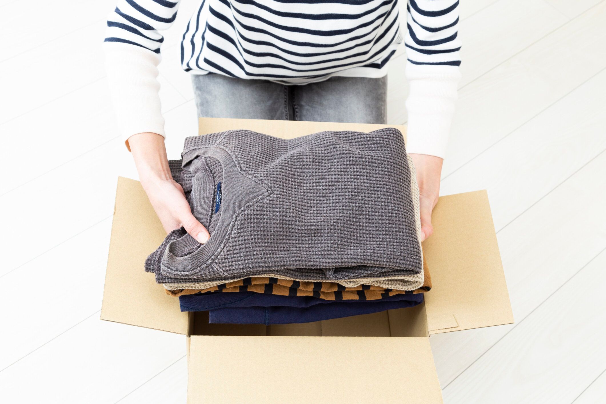 段ボール箱に衣類を詰める女性