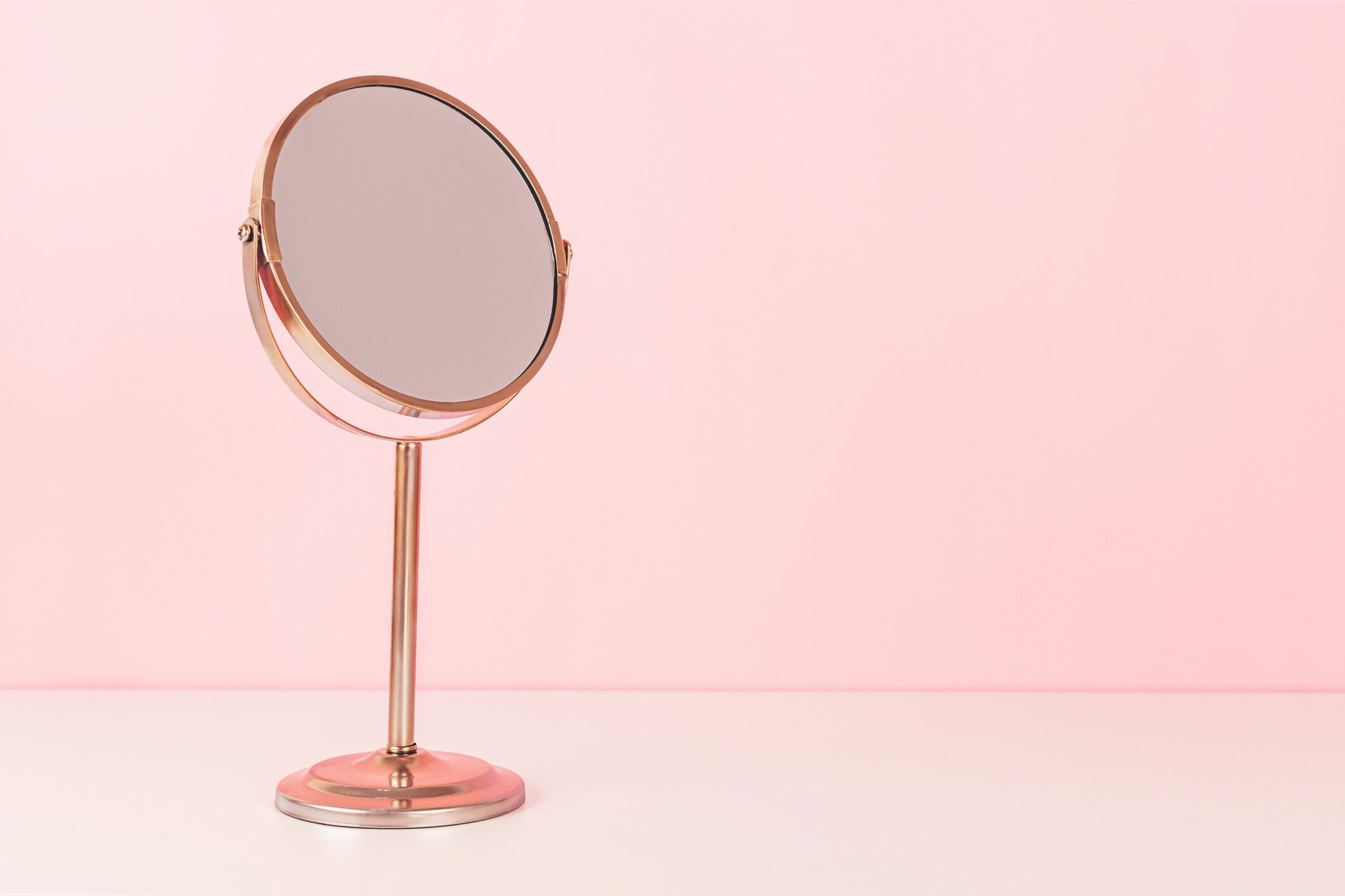 ゴールドミラーオンピンクの背景。バニティテーブルコンセプト。