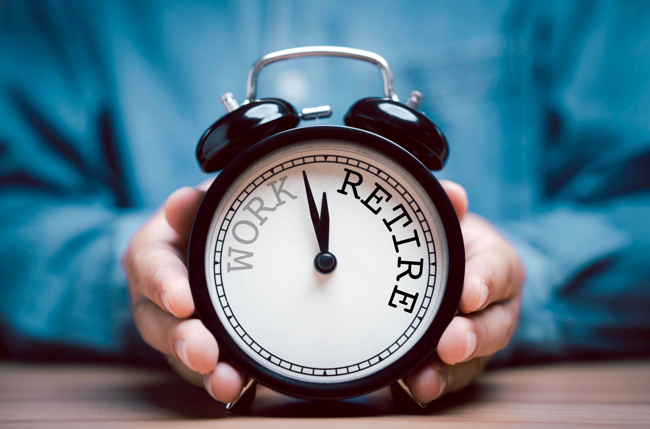 仕事から退職までの時計回りのカウントダウンを持つ黒い目覚まし時計を持つ実業家。