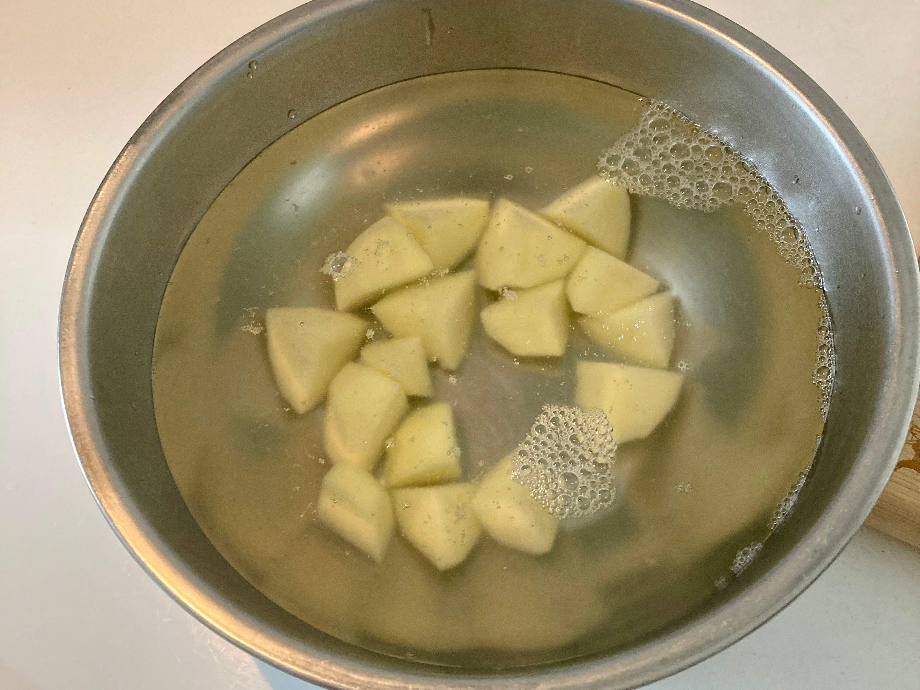 お湯に浸けられた一口大の一口大のジャガイモ