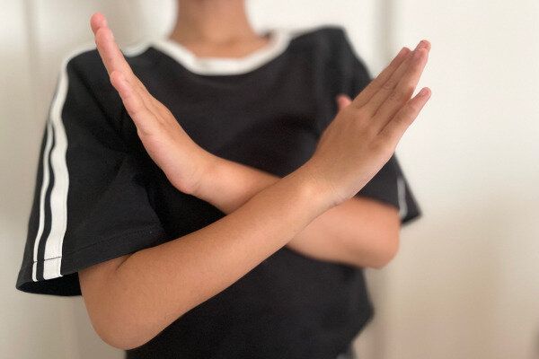 子どもが手でNOサインを出している