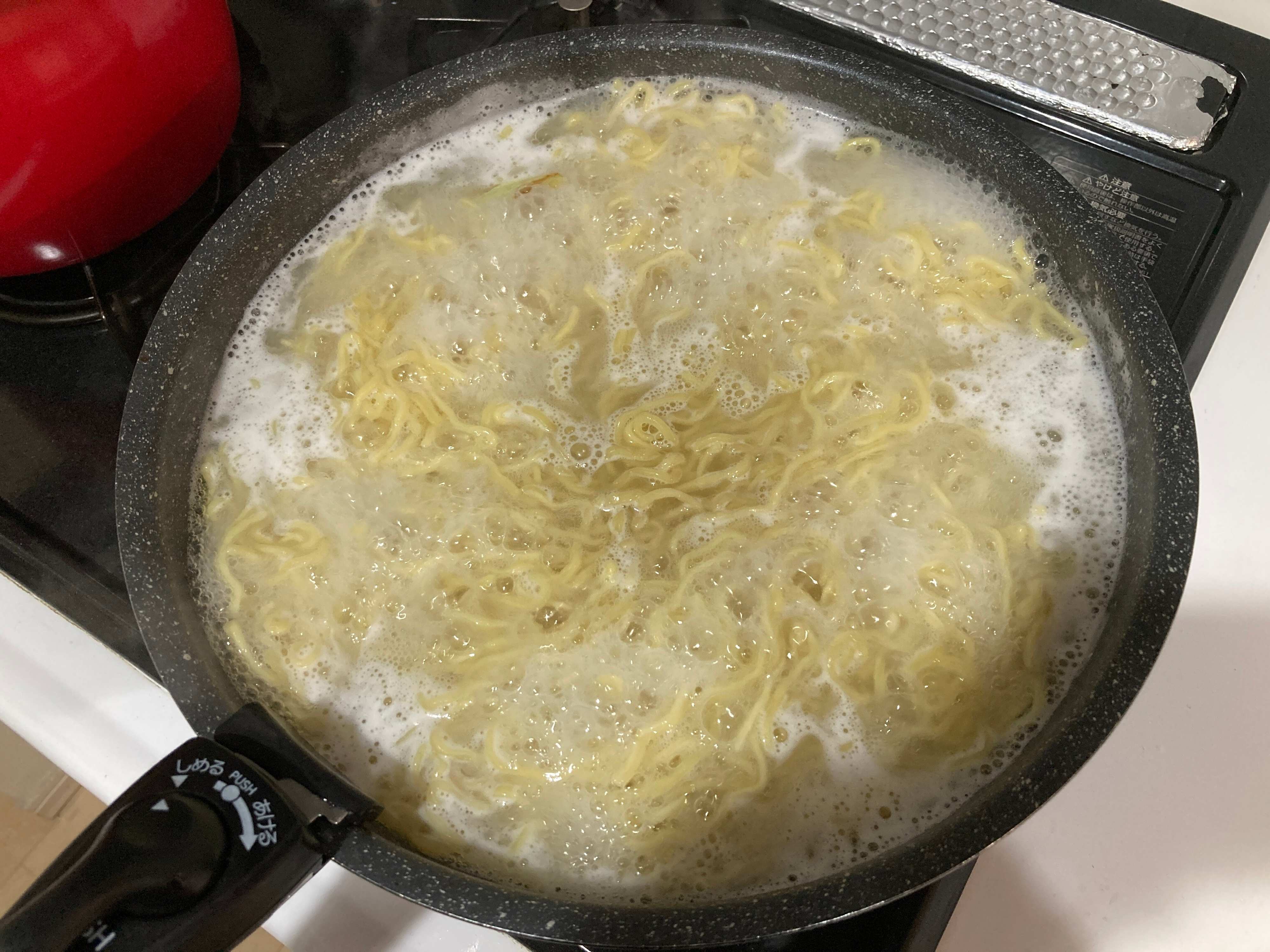 ちぢれ麺をフライパンで茹でている