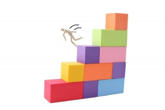 積み木の階段から踏み外して落ちそうになる人形