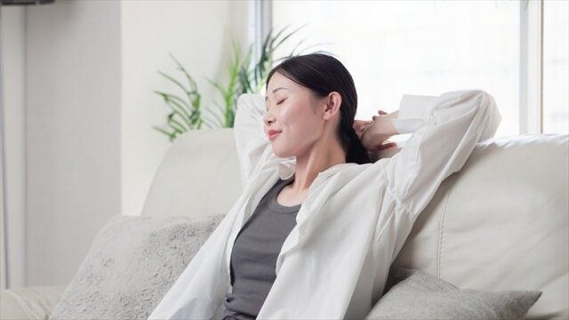 ソファで伸びをする女性
