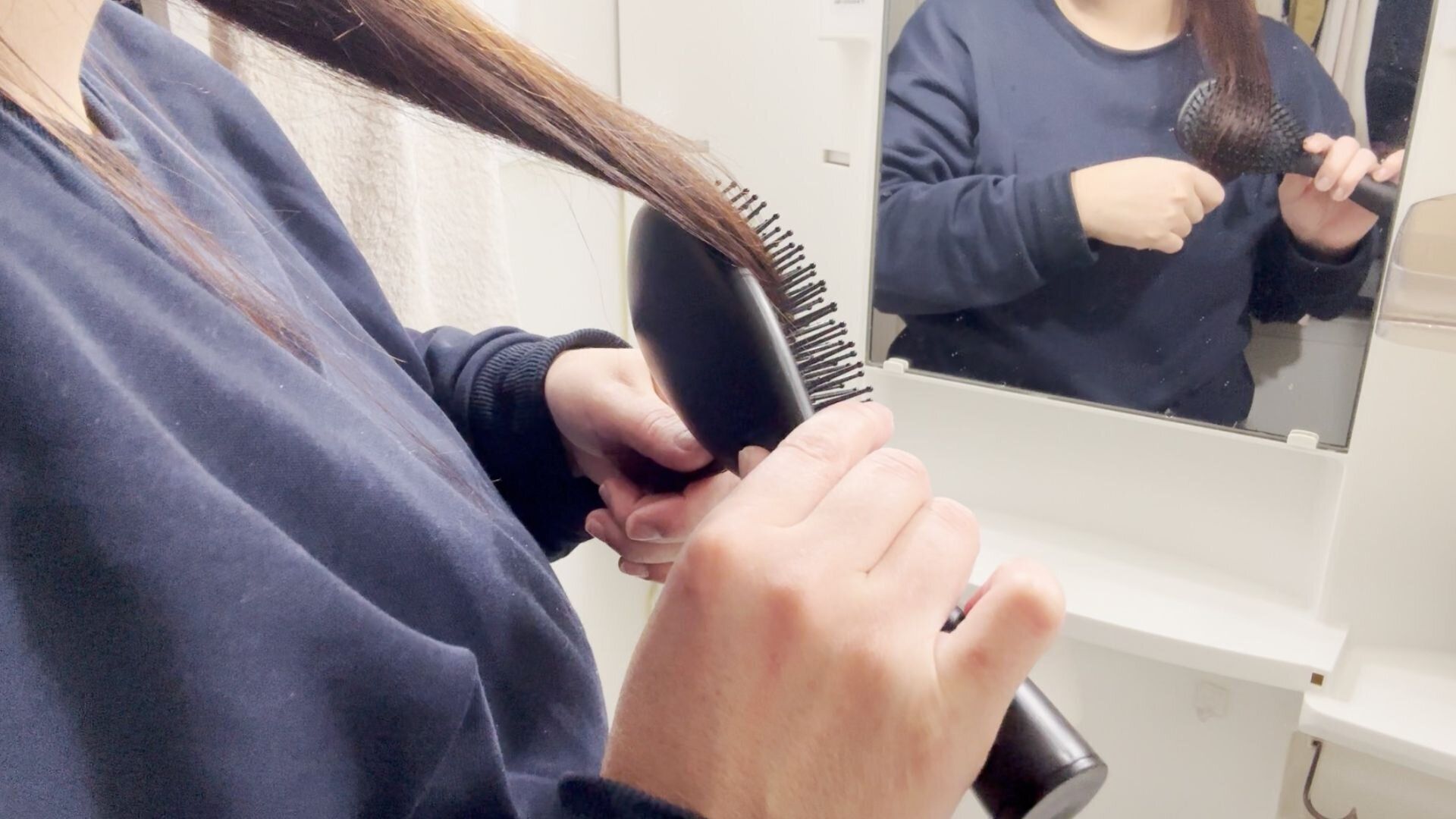 洗面ボウルの上で髪をとかす