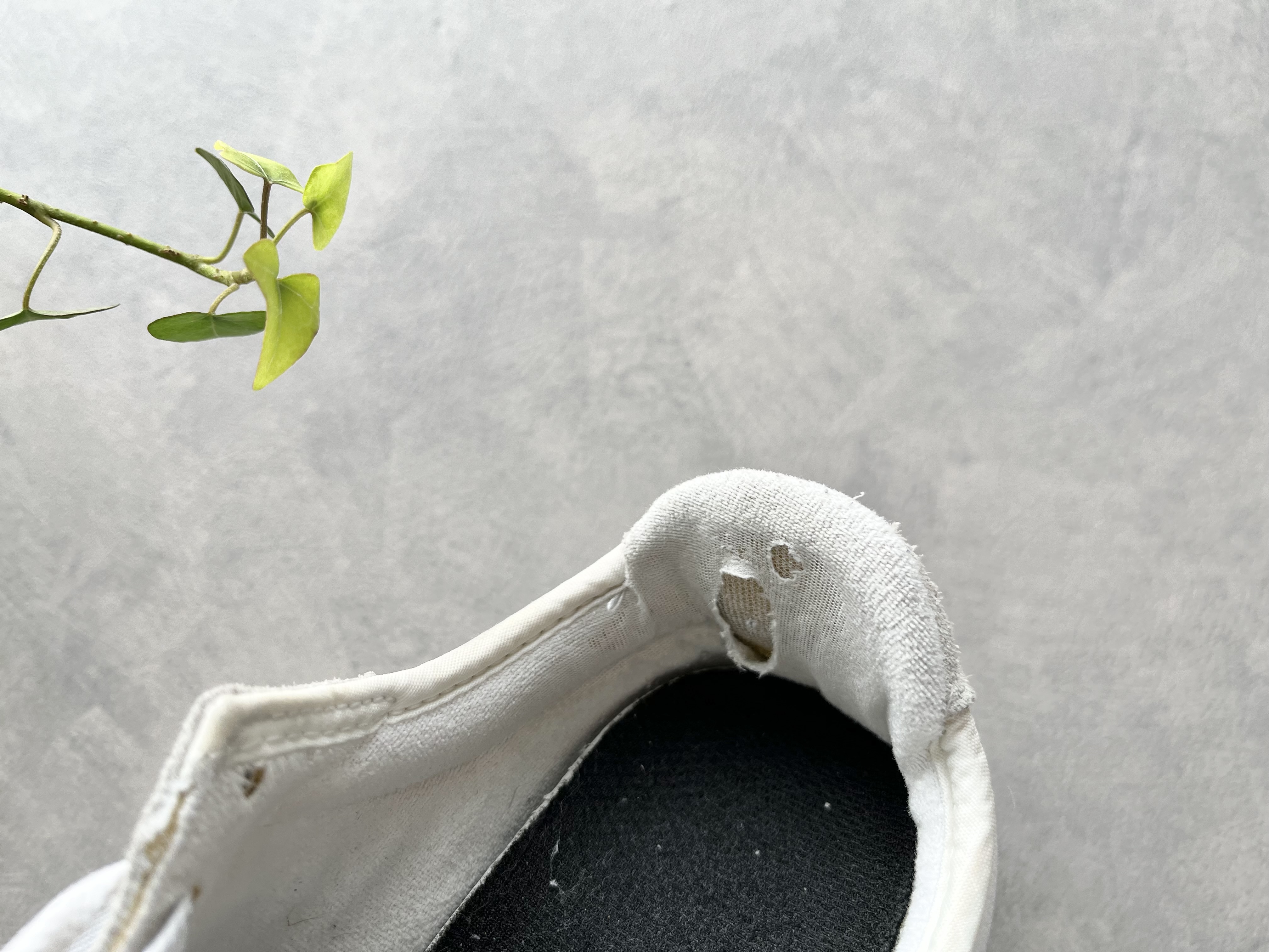 踵の内側部分が擦れて破れたスニーカーの画像