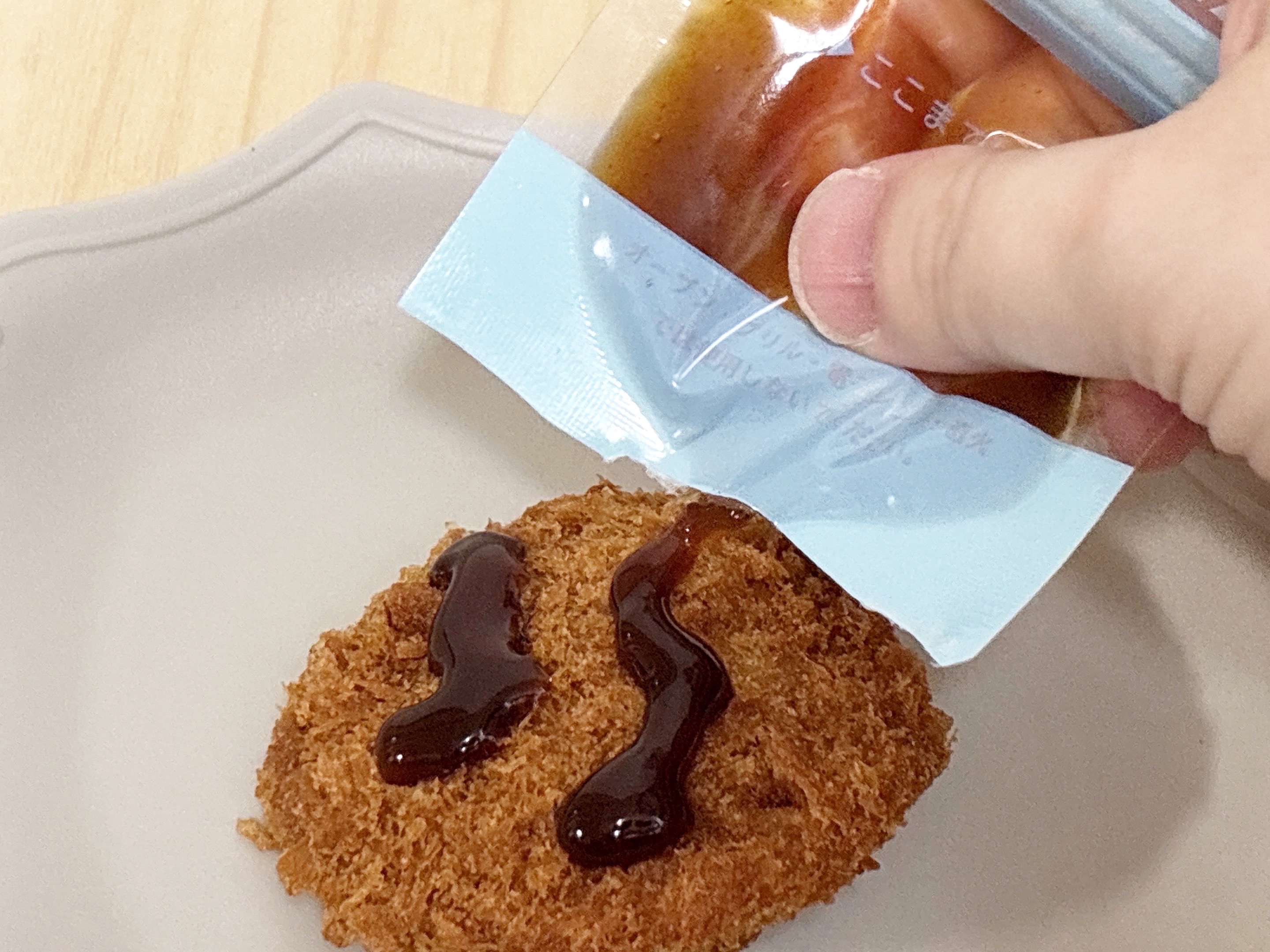 ジッパー式調味料パウチに入っているソースをおかずにつけている様子