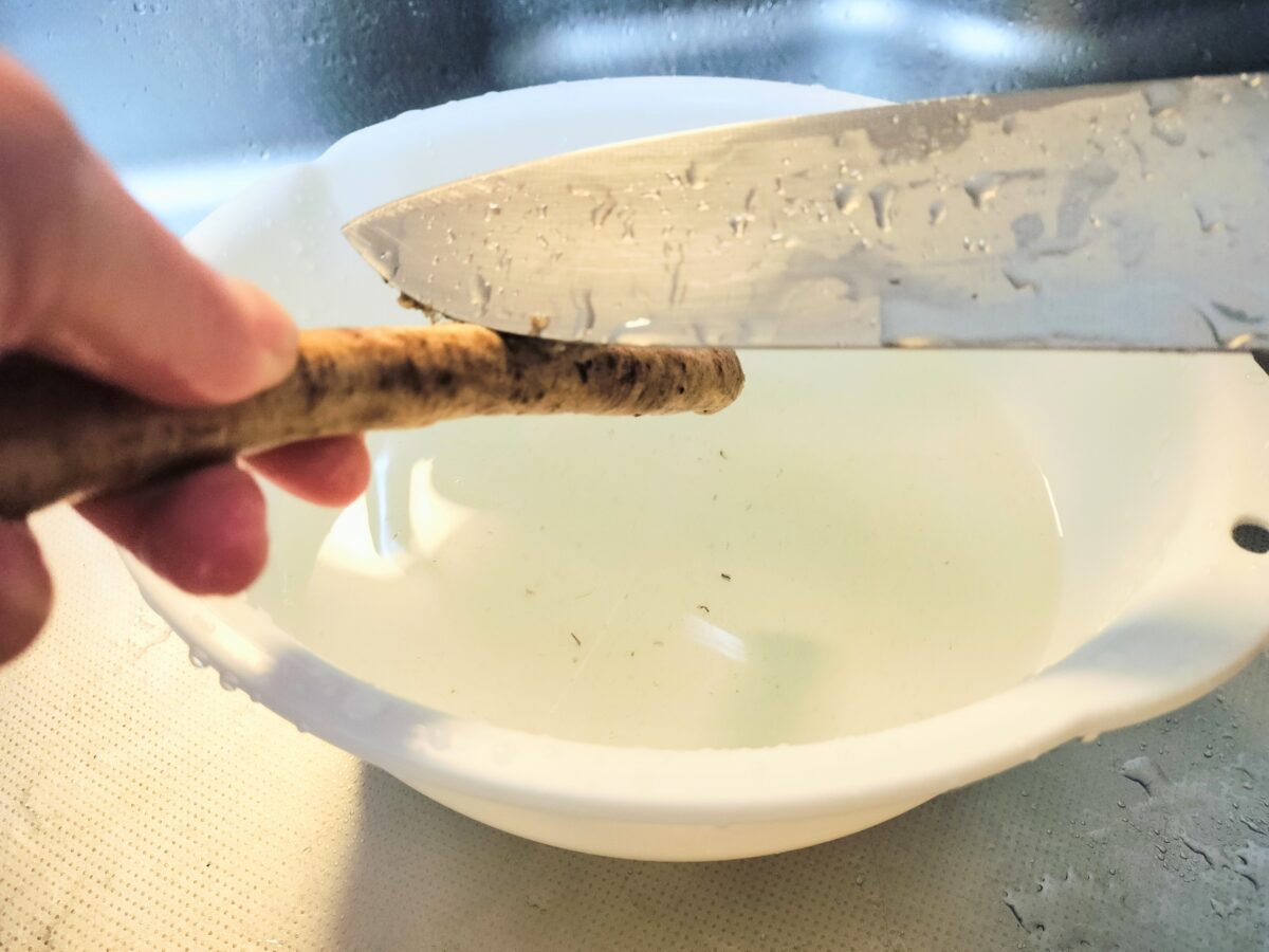 皮を包丁の背でそぐ新ごぼう