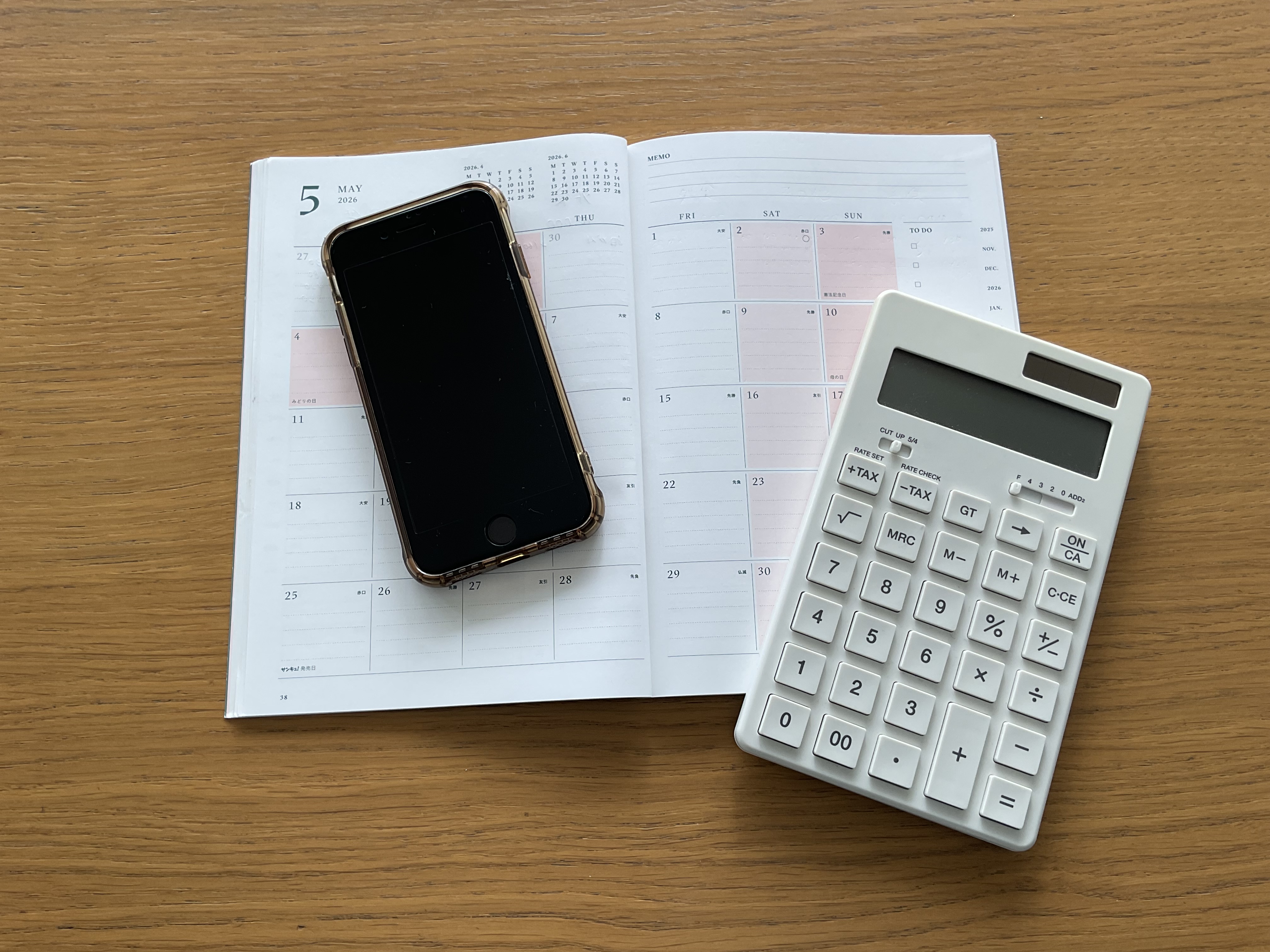 机に置かれた家計簿とスマホと電卓